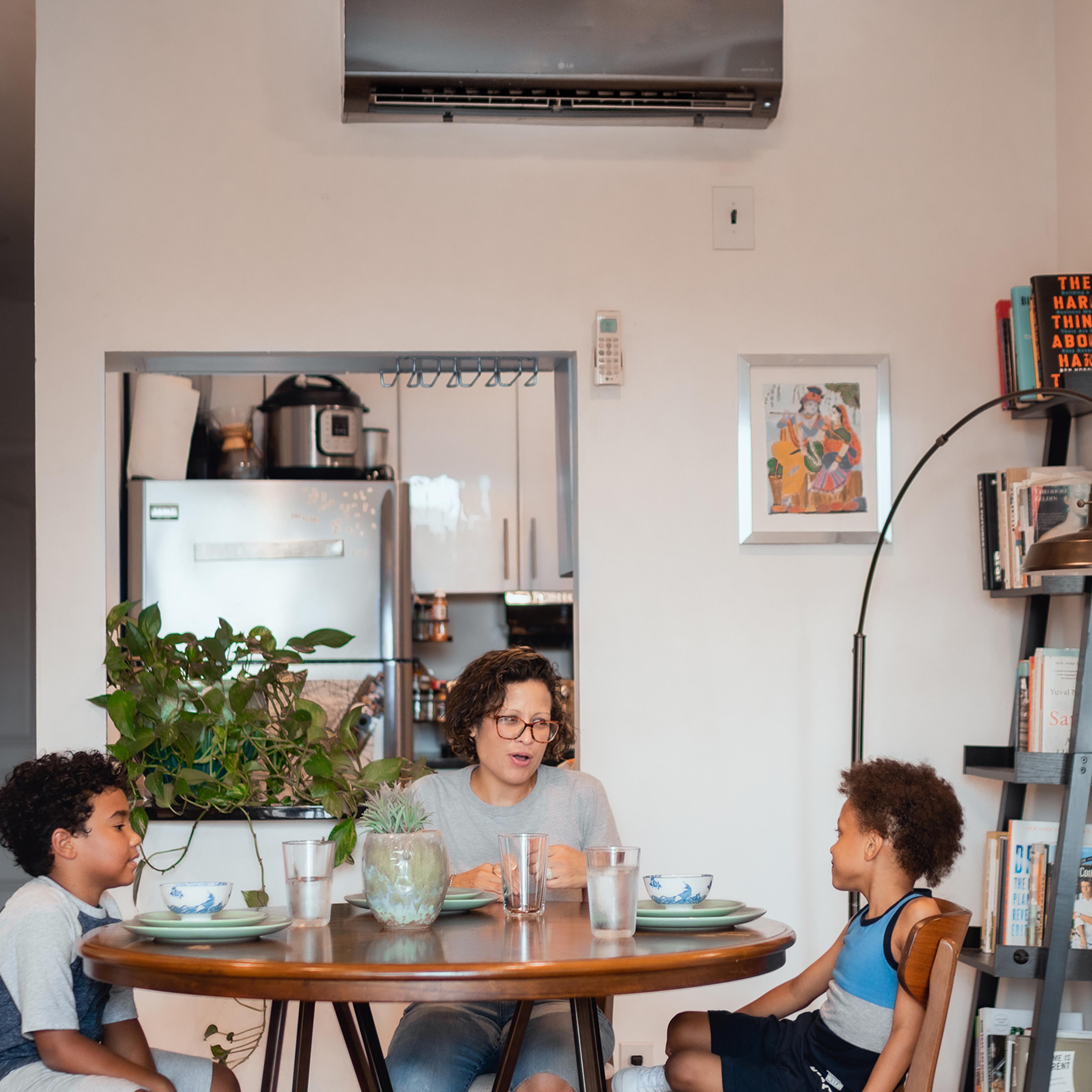 A Family in the Bedford–Stuyvesant neighborhood of Brooklyn eats dinner underneath a BlocPower heating unit.