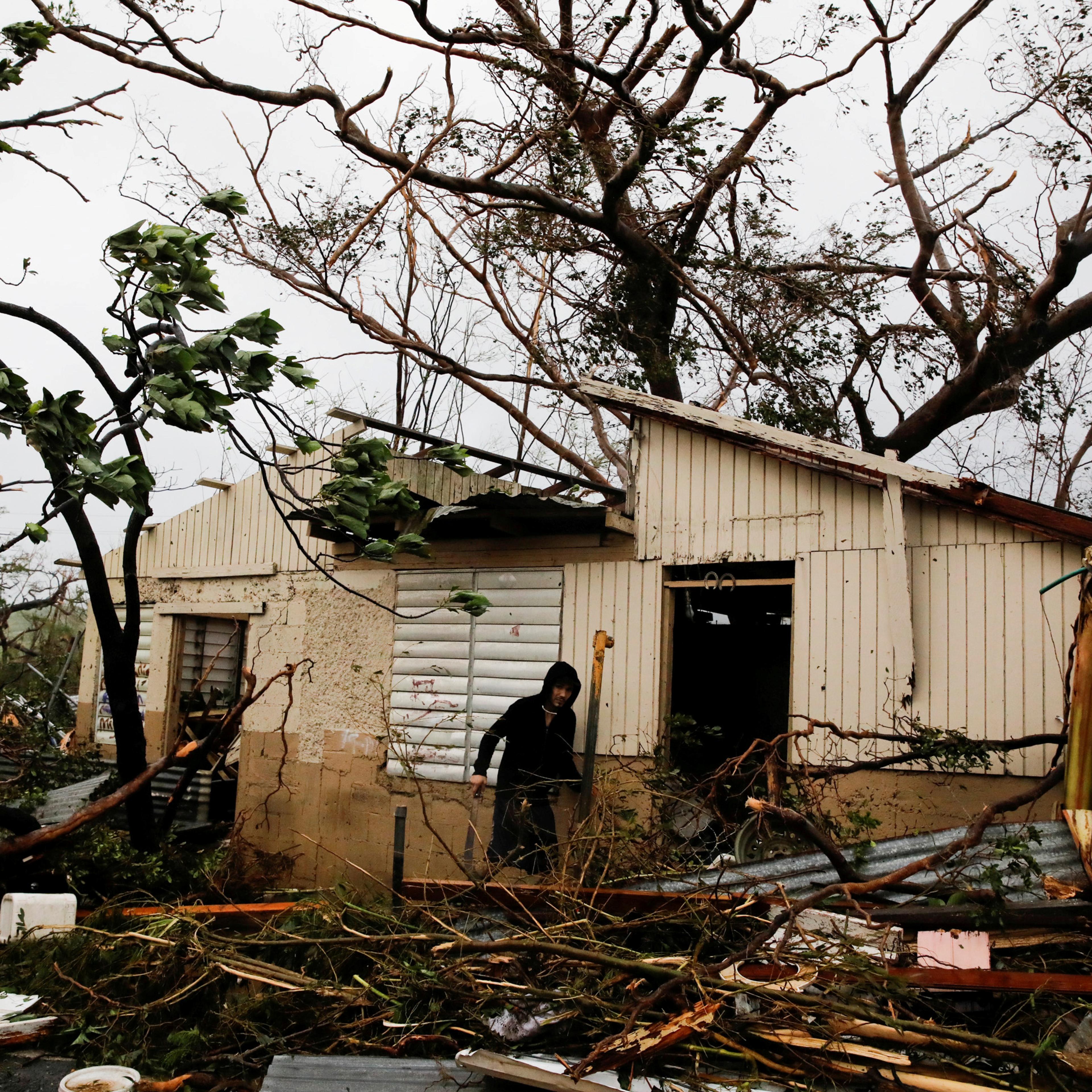 A man looks for valuables in the damaged house of a relative after the area was hit by Hurricane Maria in Guayama