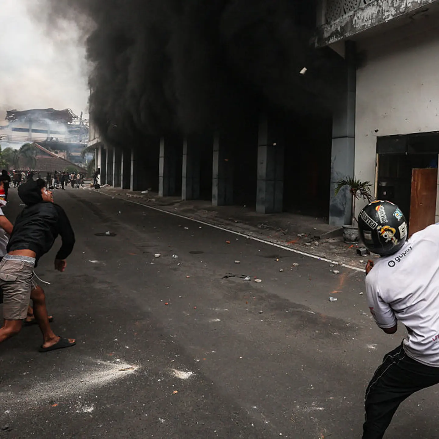 Protesters throw stones at the West Nusa Tenggara Provincial Council building, which was partially burned after being stormed, looted, and set on fire during a demonstration, in Mataram on Lombok Island, West Nusa Tenggara, on Aug. 30, 2025.