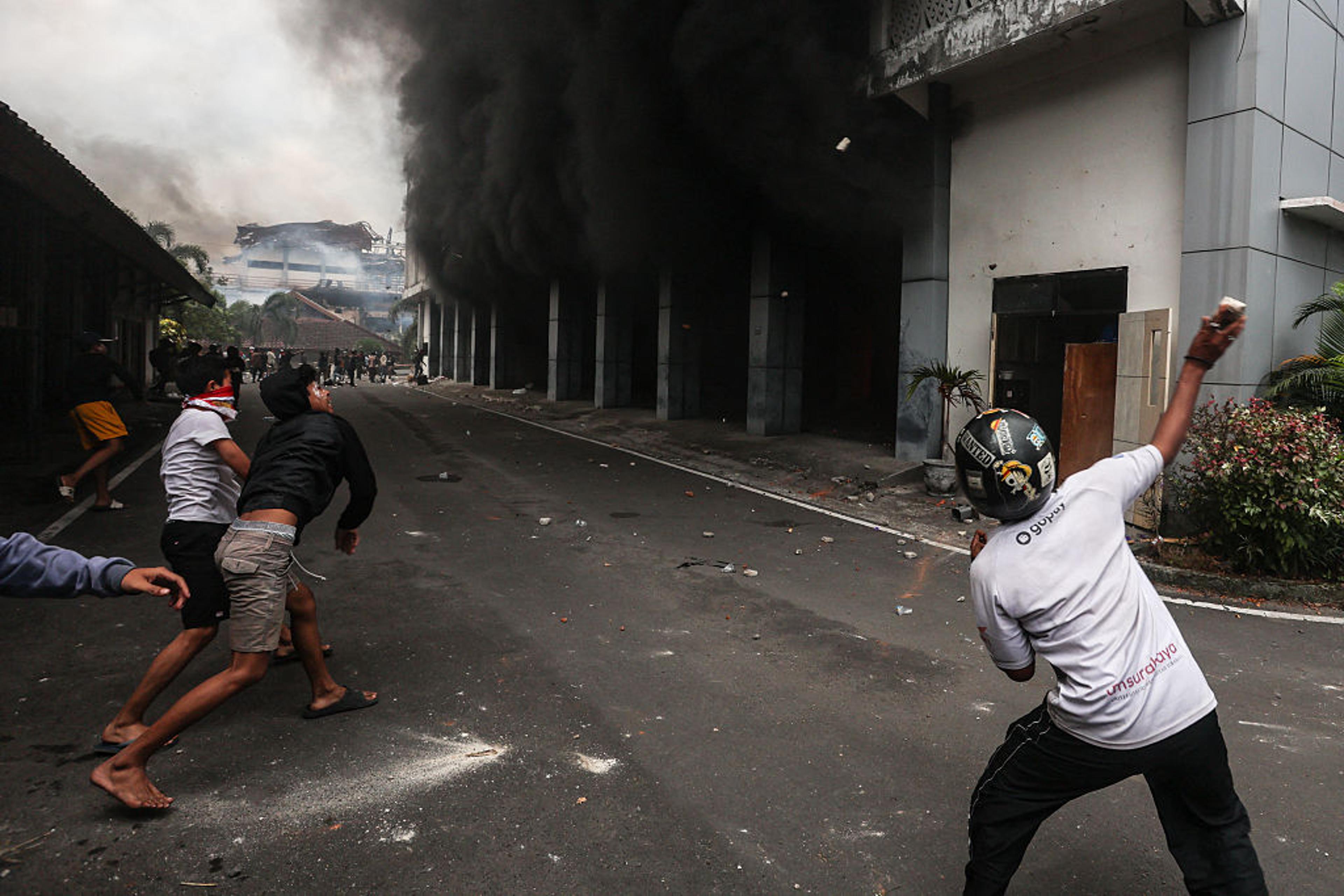 Protesters throw stones at the West Nusa Tenggara Provincial Council building, which was partially burned after being stormed, looted, and set on fire during a demonstration, in Mataram on Lombok Island, West Nusa Tenggara, on Aug. 30, 2025.