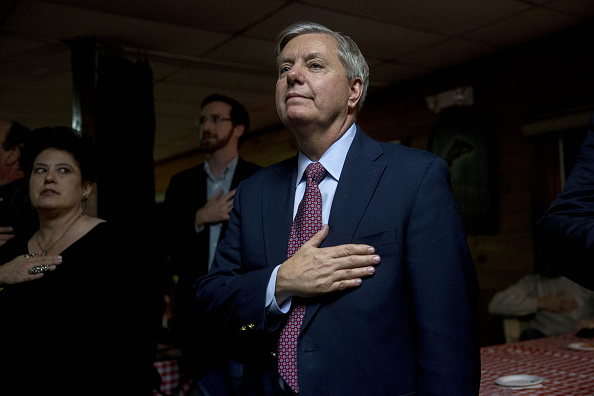 Senator Lindsey Graham, a Republican from South Carolina and 2016 presidential candidate, right, places his hand over his heart during the Pledge of Allegiance at the Stafford County GOP Christmas Party during a campaign stop at Newick's Lobster House in