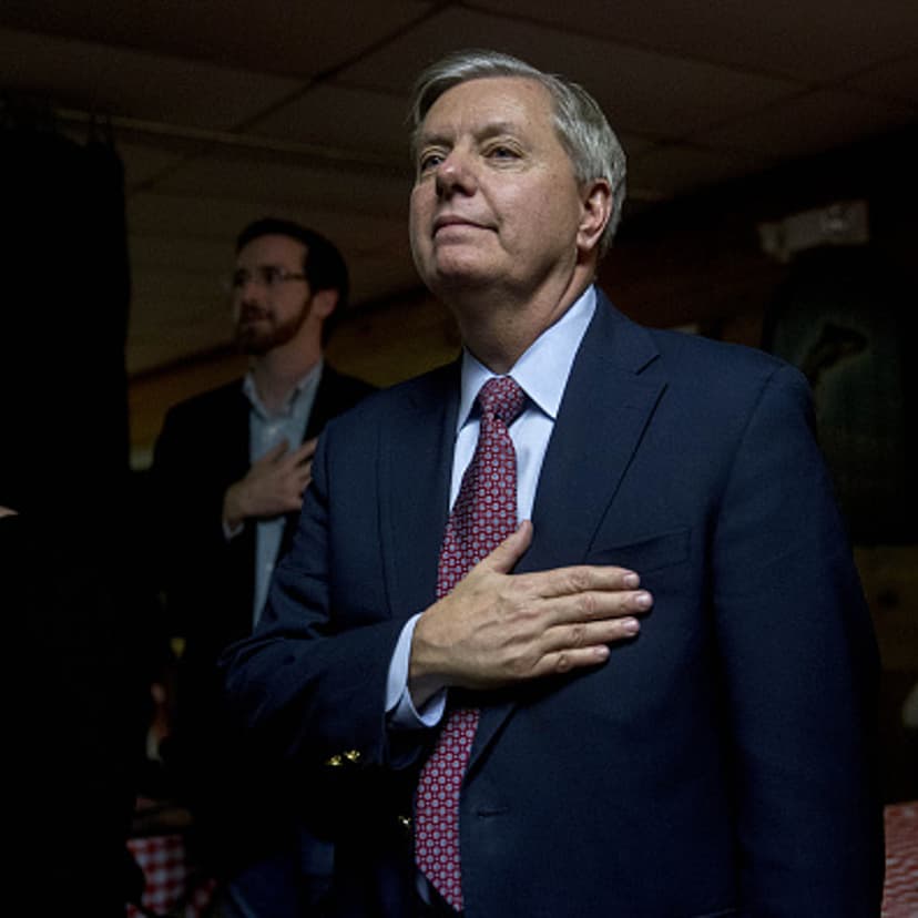 Senator Lindsey Graham, a Republican from South Carolina and 2016 presidential candidate, right, places his hand over his heart during the Pledge of Allegiance at the Stafford County GOP Christmas Party during a campaign stop at Newick's Lobster House in