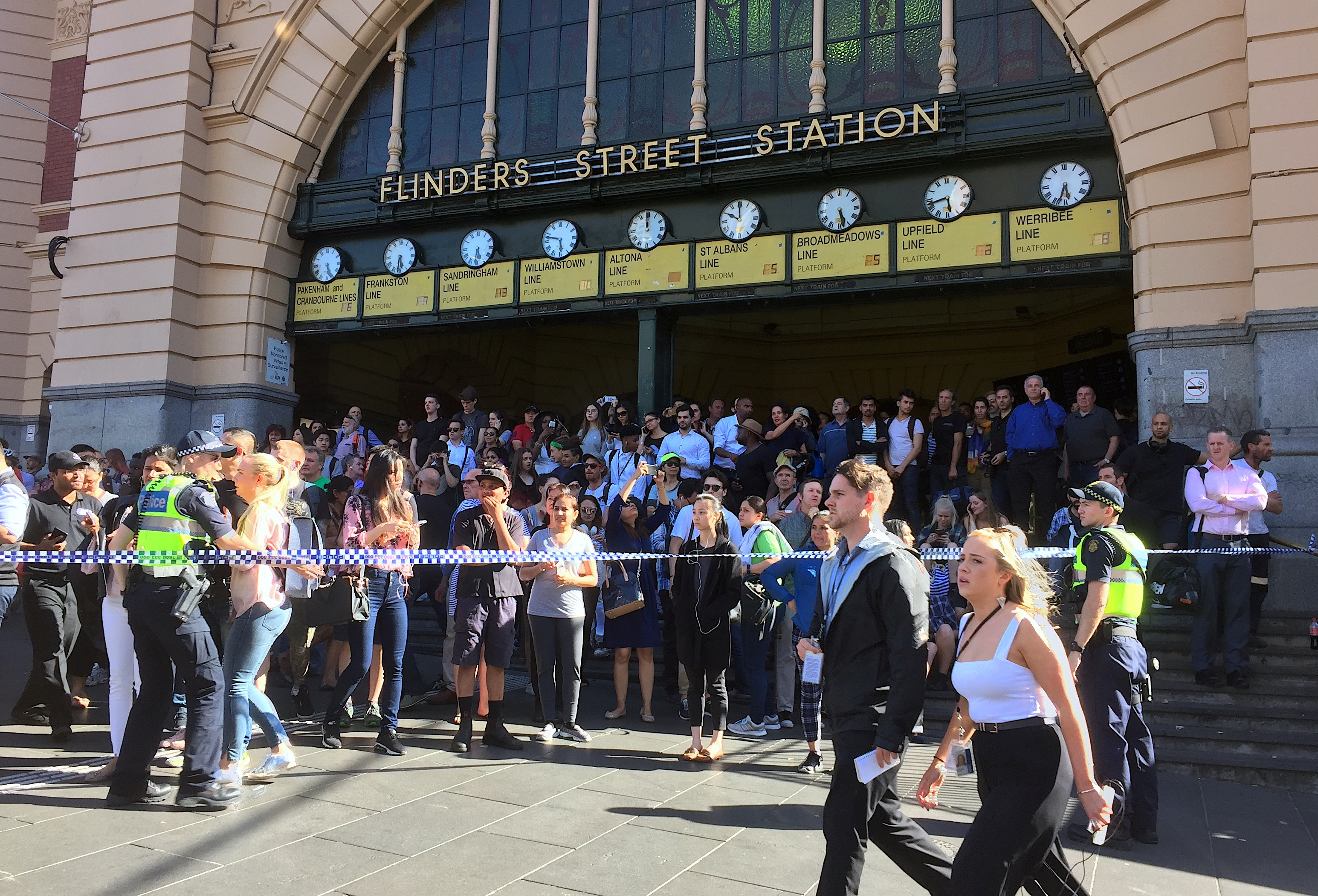 Members of the public stand behind police tape after Australian police said on Thursday they have arrested the driver of a vehicle that ploughed into pedestrians at a crowded intersection near the Flinders Street train station in central Melbourne