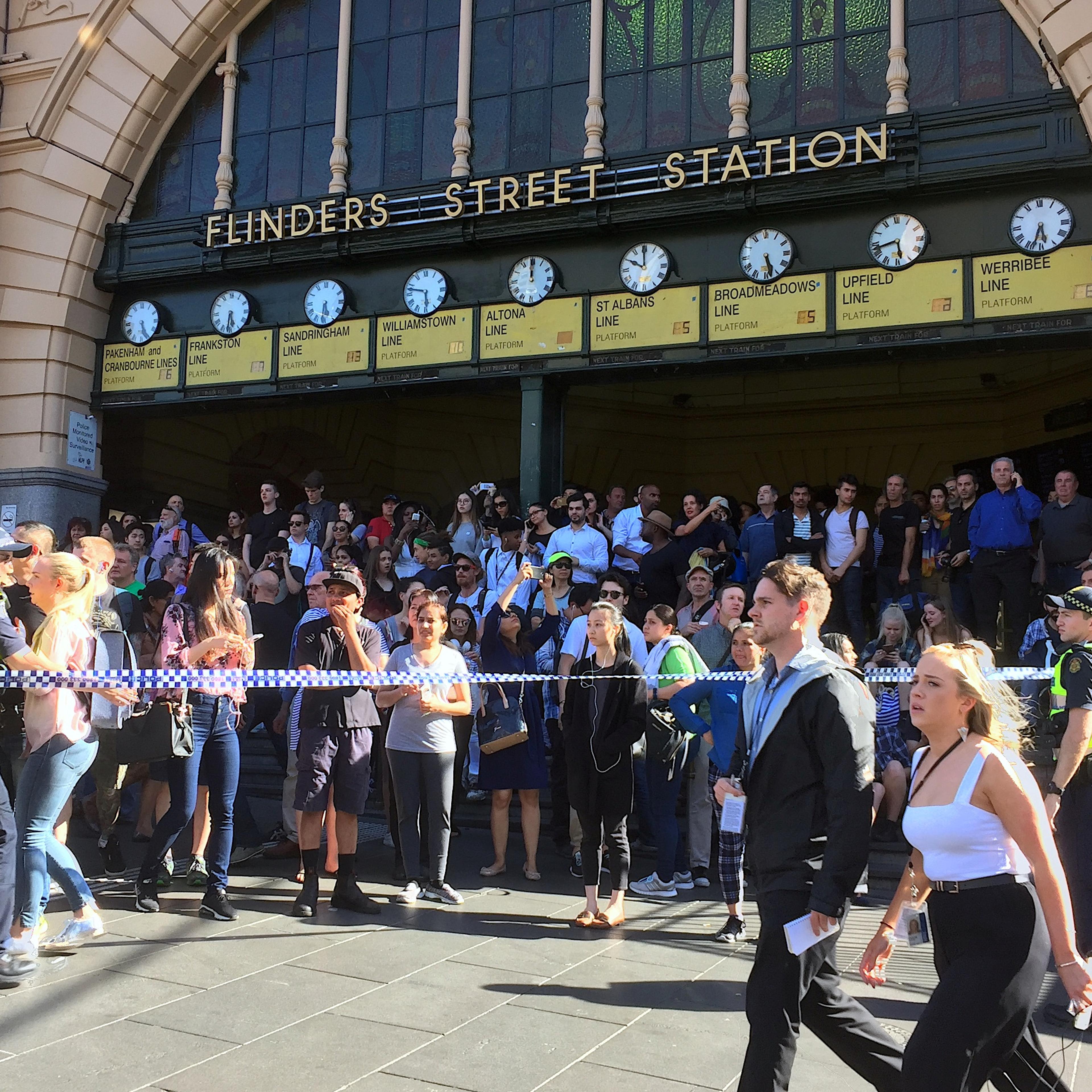 Members of the public stand behind police tape after Australian police said on Thursday they have arrested the driver of a vehicle that ploughed into pedestrians at a crowded intersection near the Flinders Street train station in central Melbourne