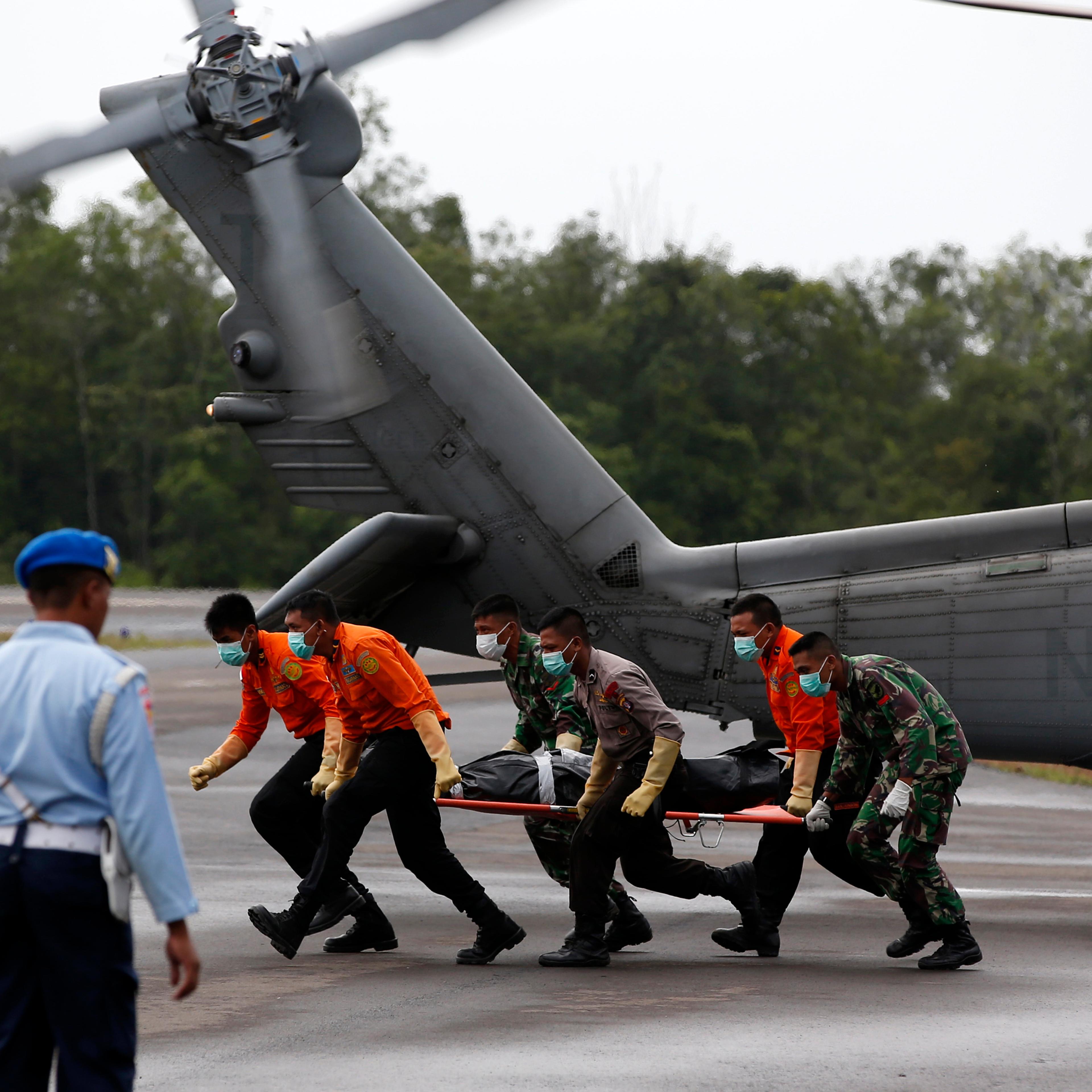 The body of an AirAsia QZ8501 passenger is carried to an ambulance after being transported from a ship by a U.S. Navy helicopter from the USS Sampson at the airbase in Pangkalan Bun