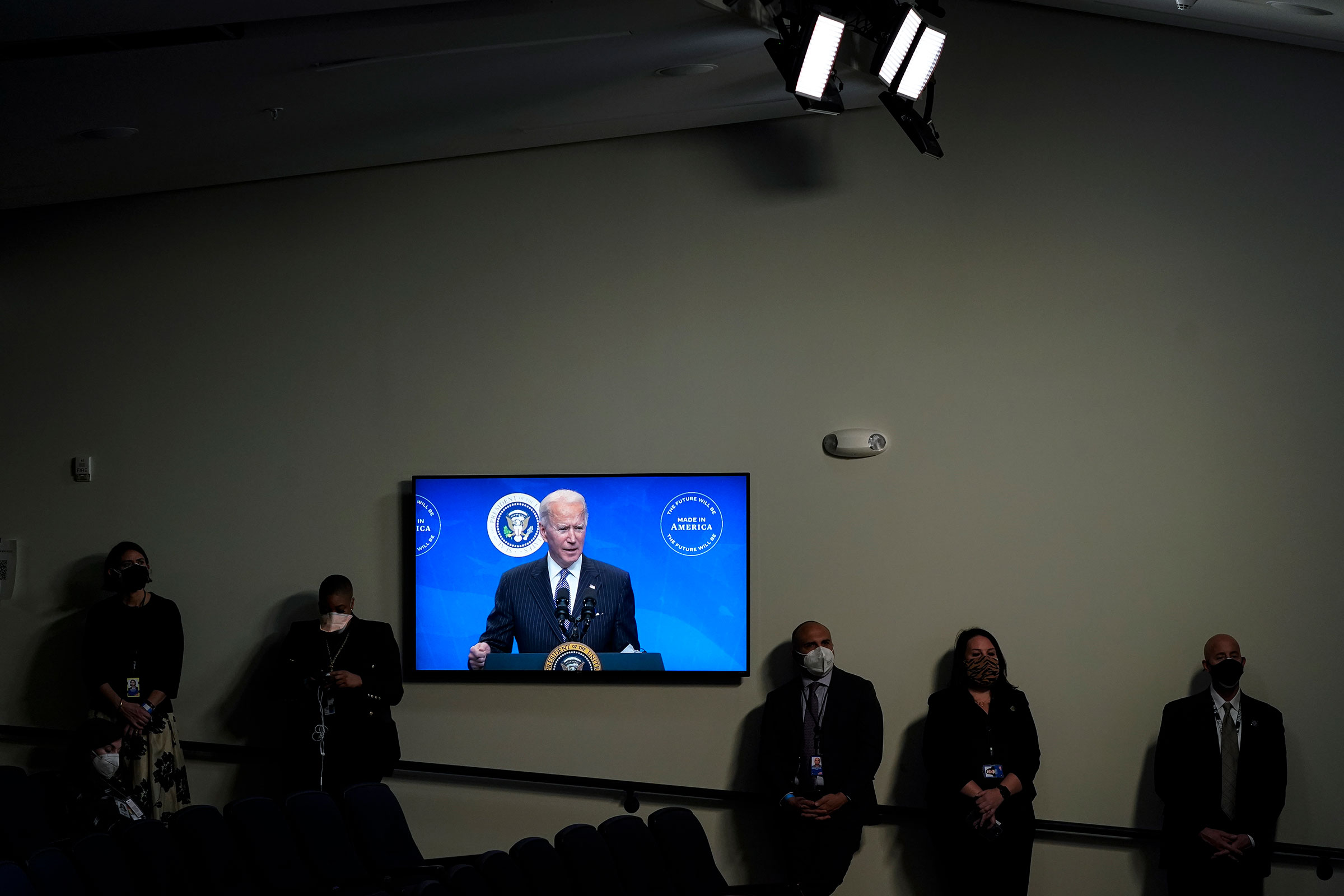 President Joe Biden is displayed on a screen while speaking after signing an executive order in the South Court Auditorium of the White House complex on Jan. 25, 2021.