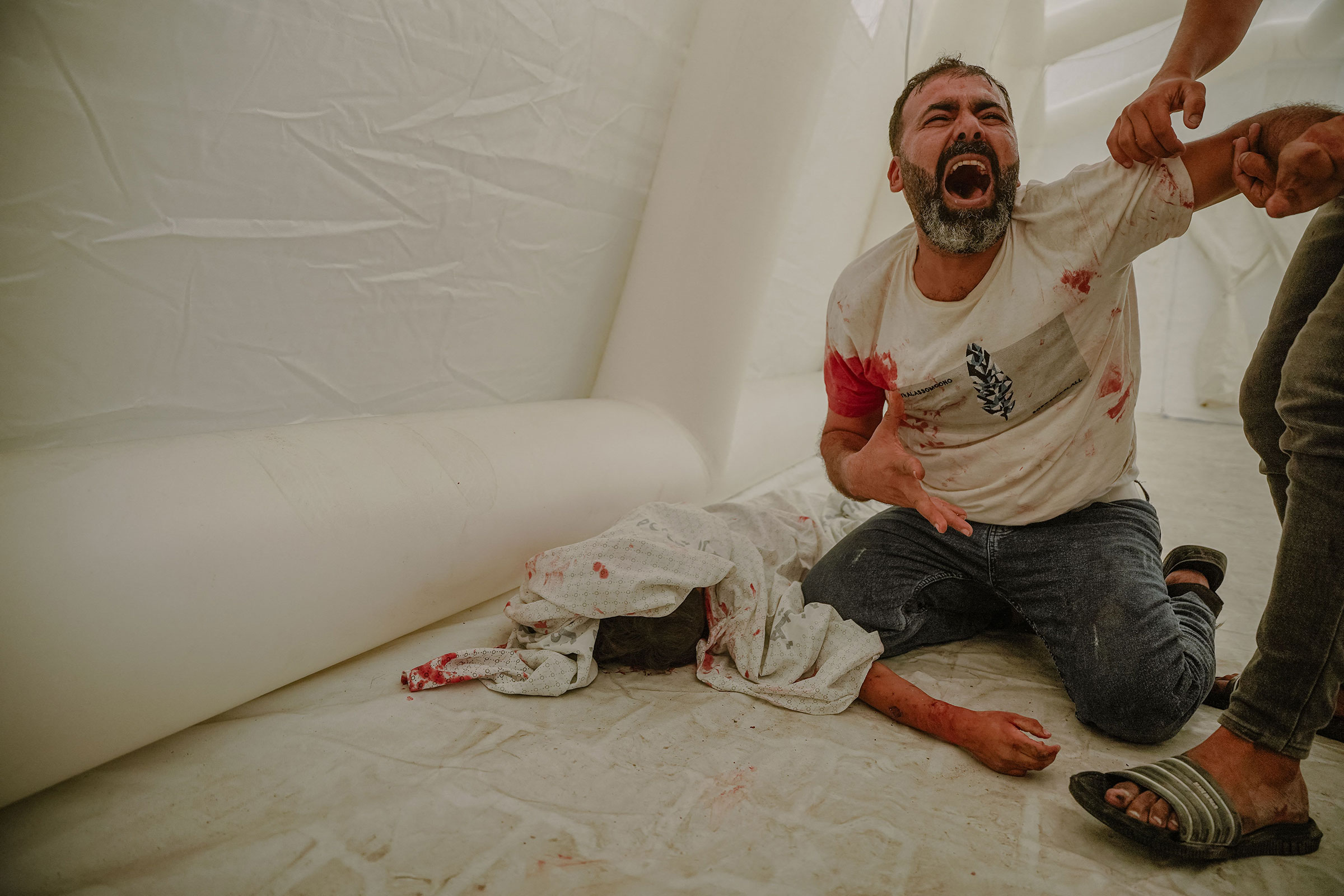 Omar Lafi grieves as he clings to the lifeless body of his nephew, who fell victim to an Israeli airstrike in Gaza City, on Oct. 9.