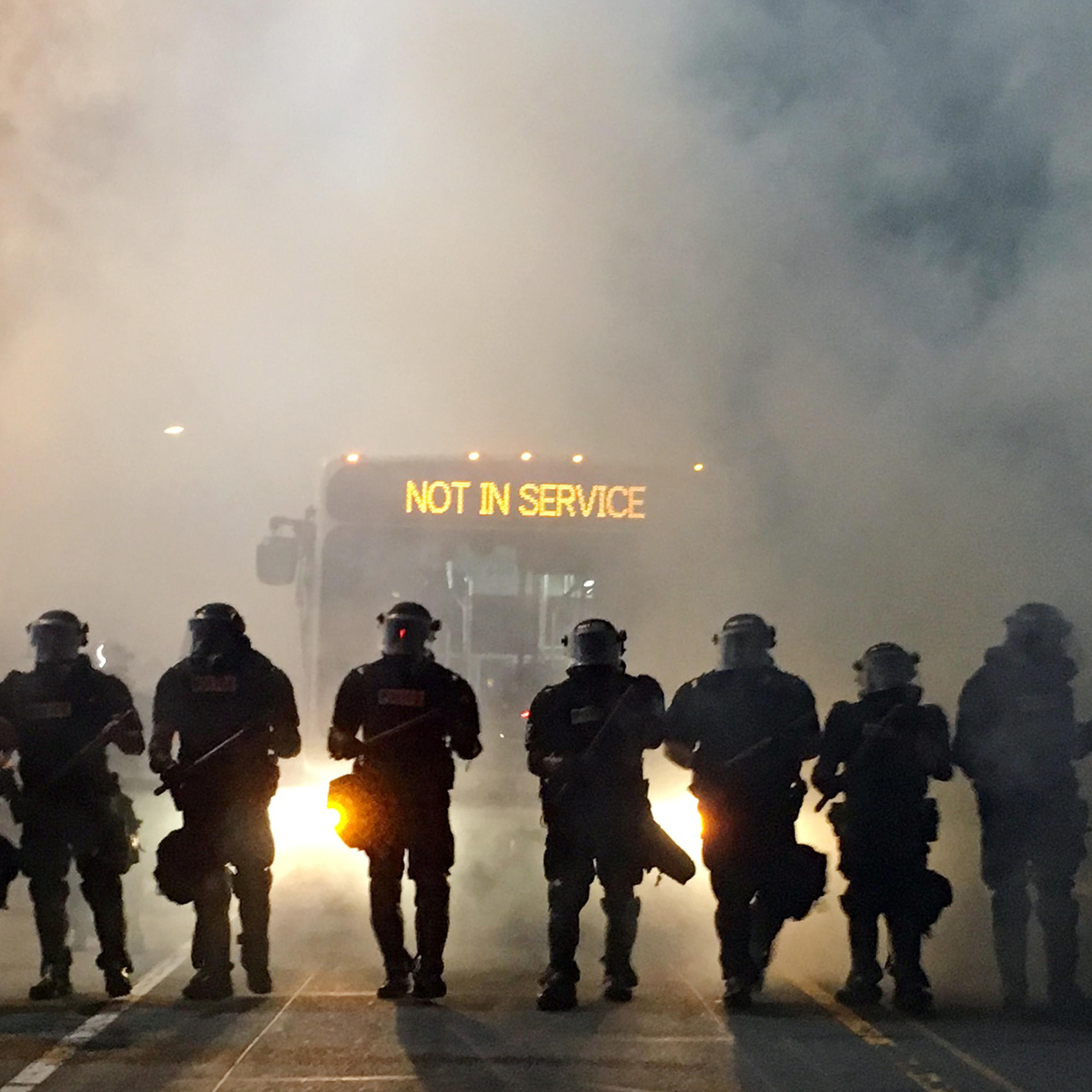 Police officers wearing riot gear block a road during protests after police fatally shot a man in the parking lot of an apartment complex in Charlotte