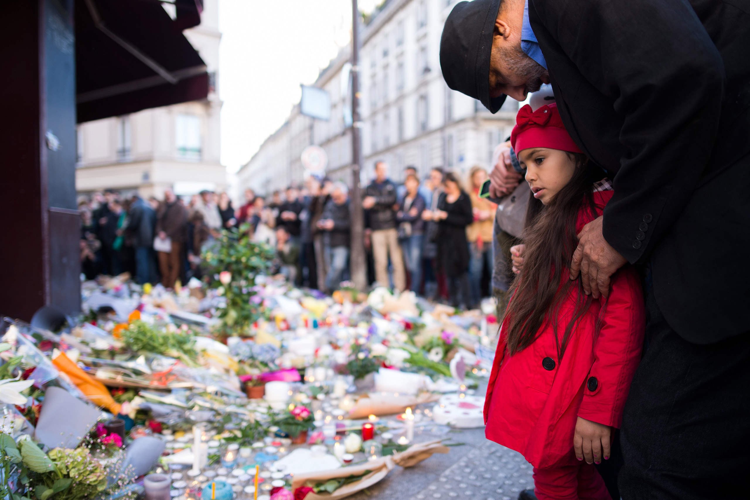 15 Nov 2015, Paris, France --- A child and a man have gathered to grieve in front of the CafÈ Carillon in the Rue Alibert where candles and flowers have been laid in Paris, France, 15 November 2015. At least 129 people were killed in a series of terroris
