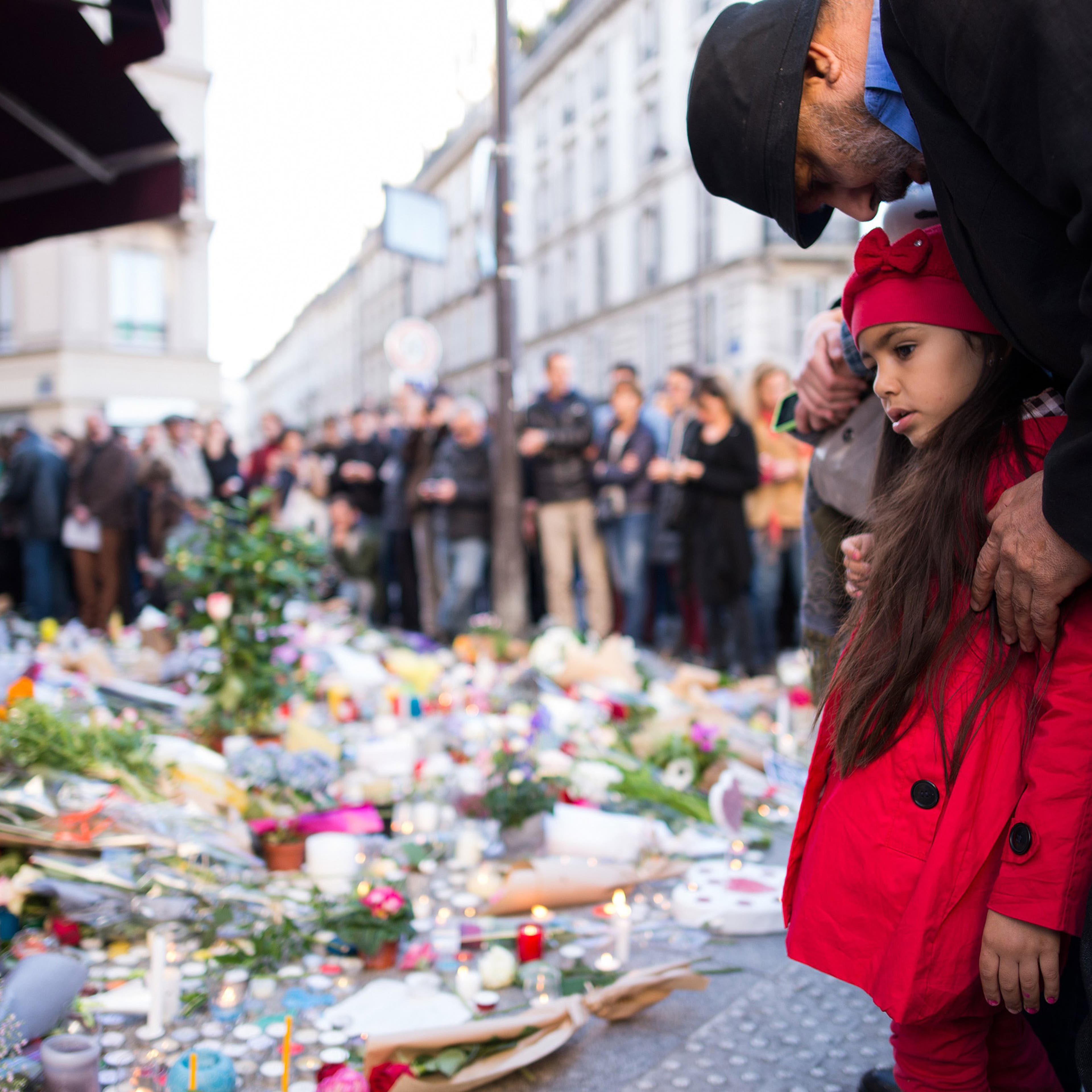 15 Nov 2015, Paris, France --- A child and a man have gathered to grieve in front of the CafÈ Carillon in the Rue Alibert where candles and flowers have been laid in Paris, France, 15 November 2015. At least 129 people were killed in a series of terroris