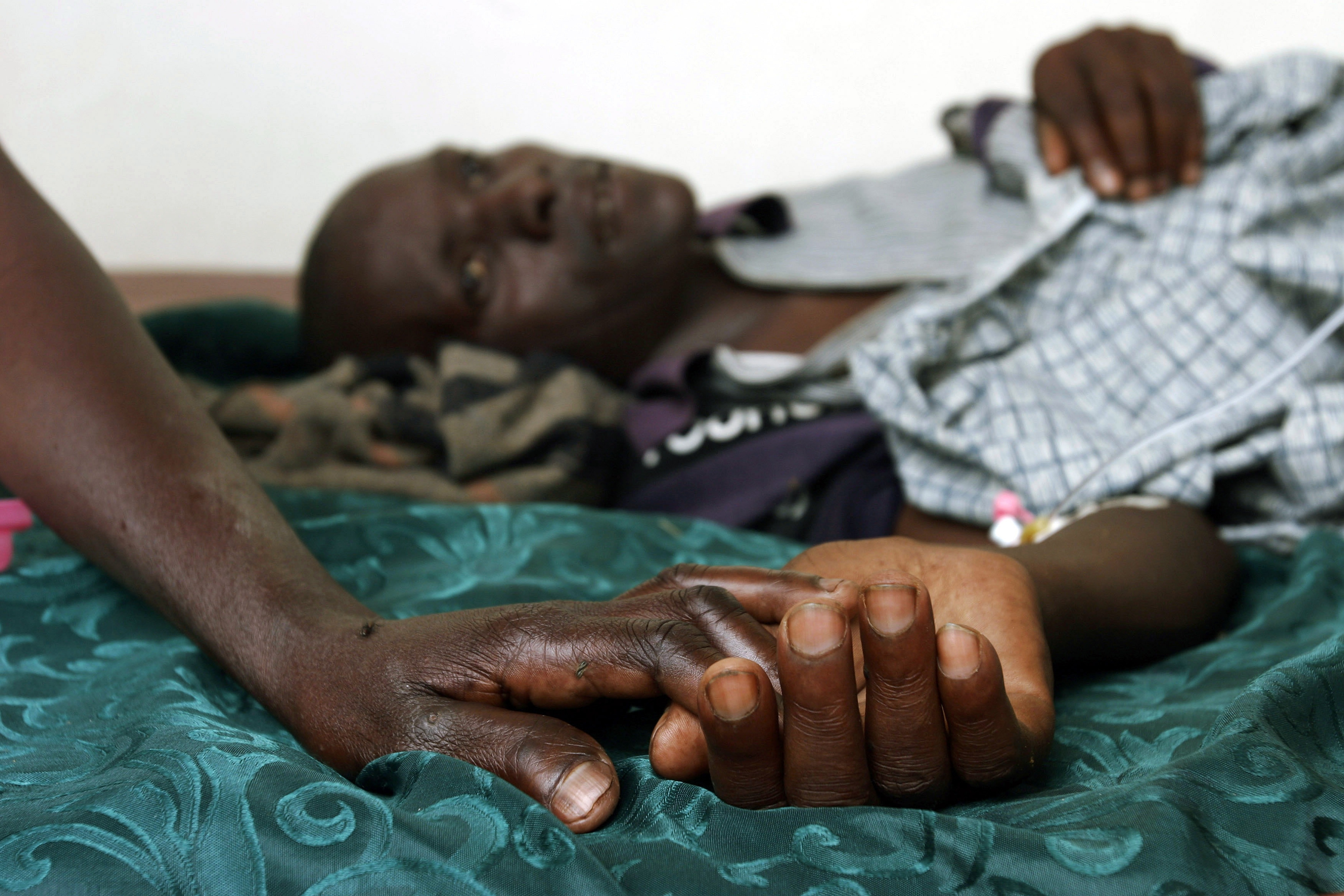 A mother holds the hand of her Aids stricken son in Rakai, Ugand