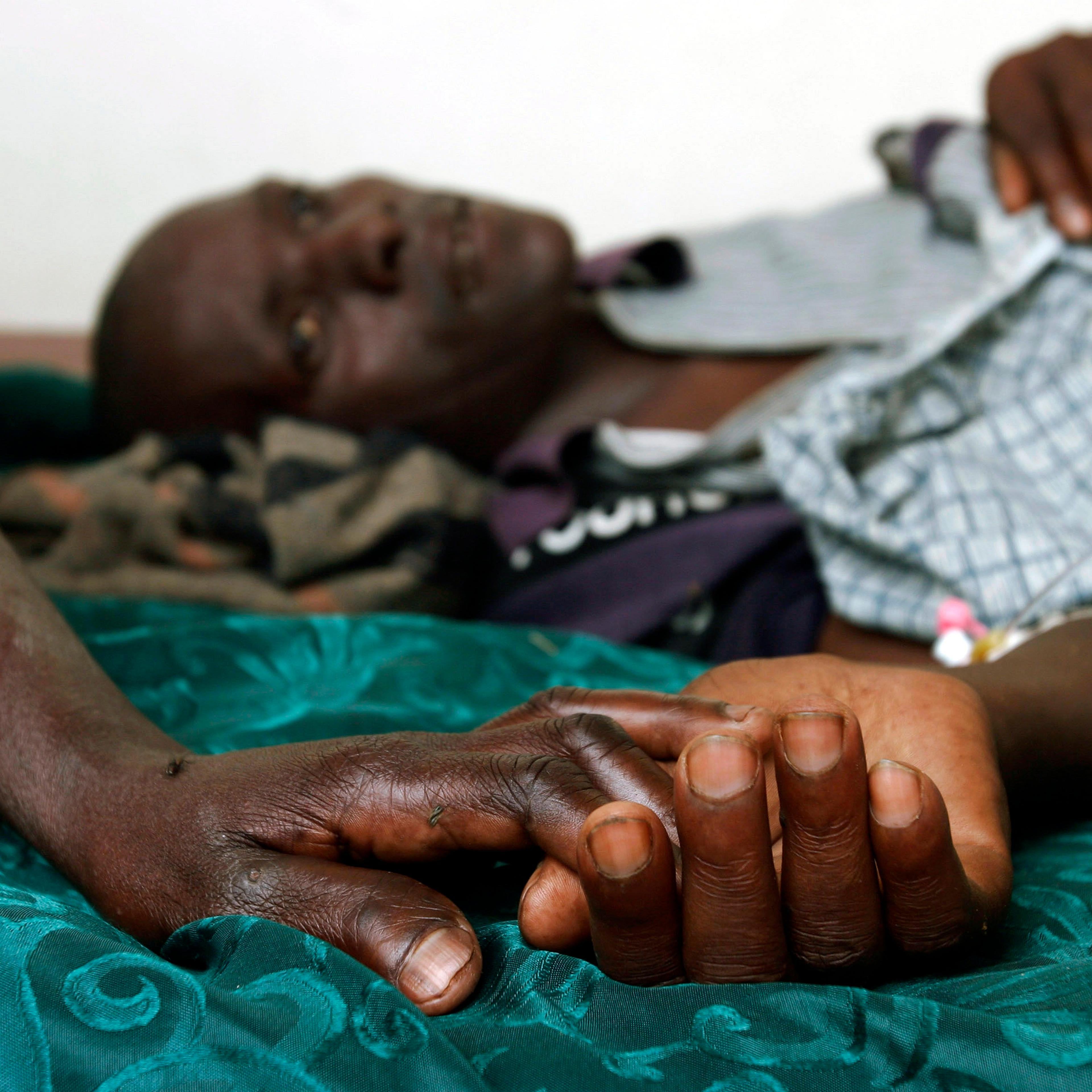 A mother holds the hand of her Aids stricken son in Rakai, Ugand