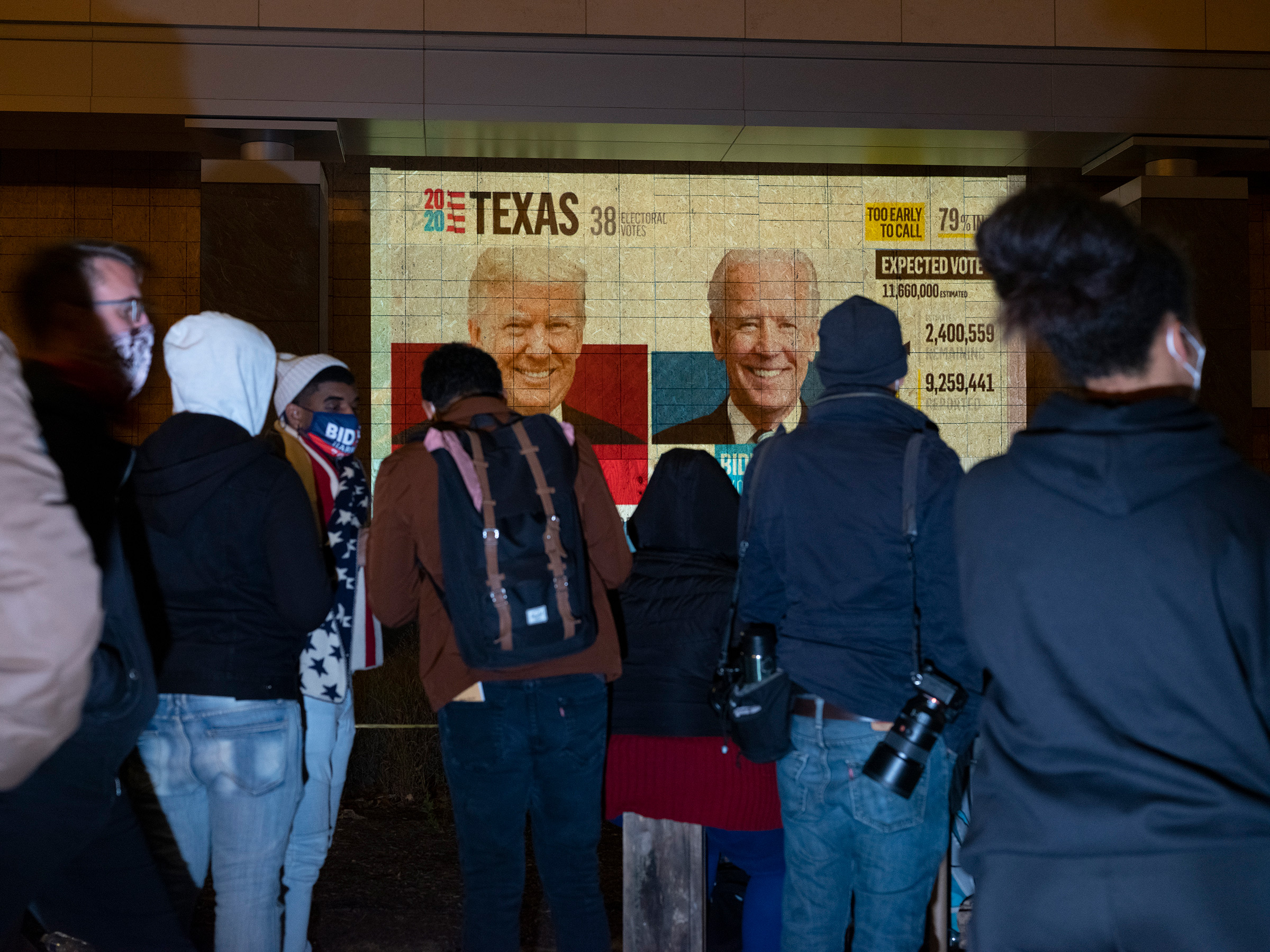 People watch a projector on a boarded up storefront in Lafayette Square, Washington D.C., Nov. 3, 2020.