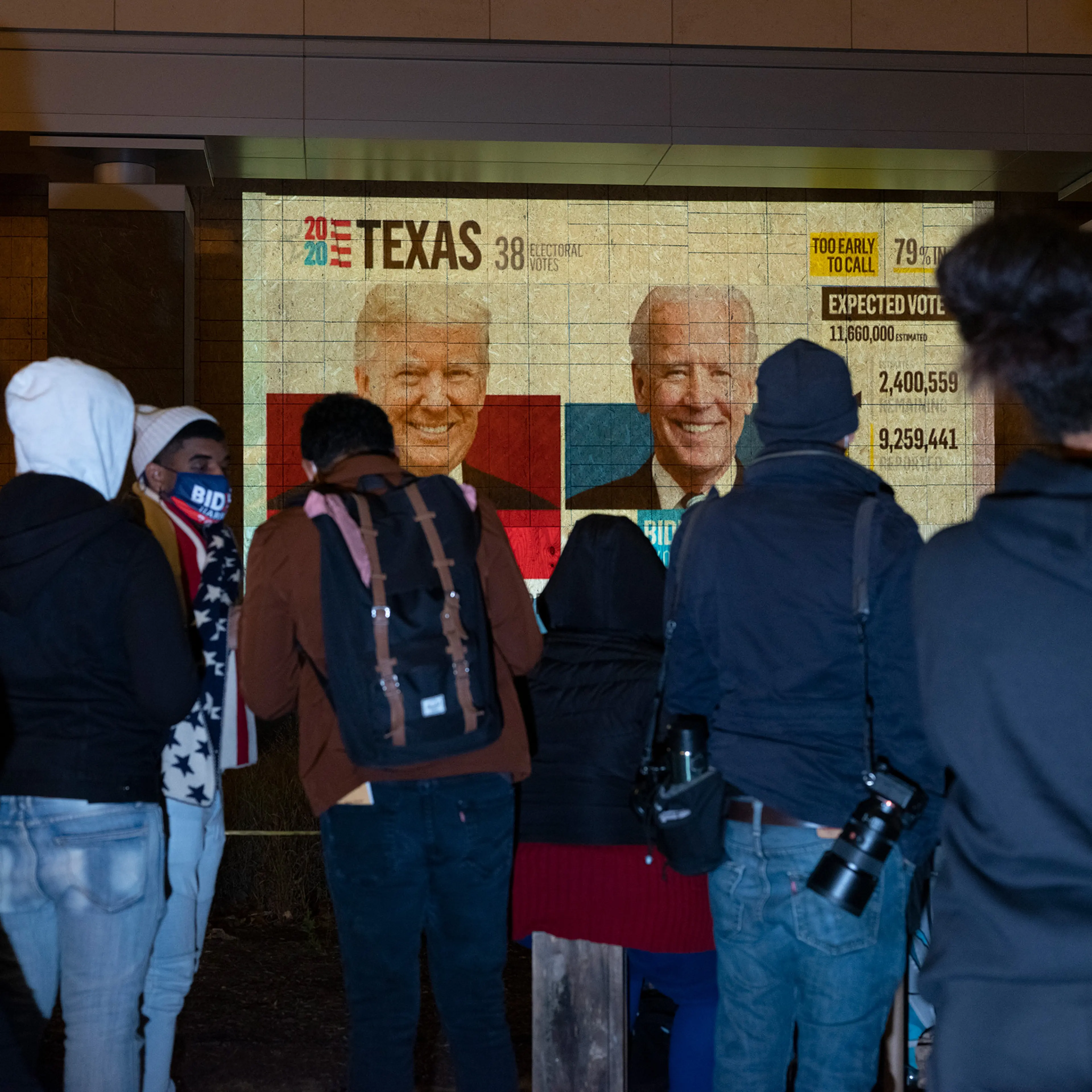 People watch a projector on a boarded up storefront in Lafayette Square, Washington D.C., Nov. 3, 2020.