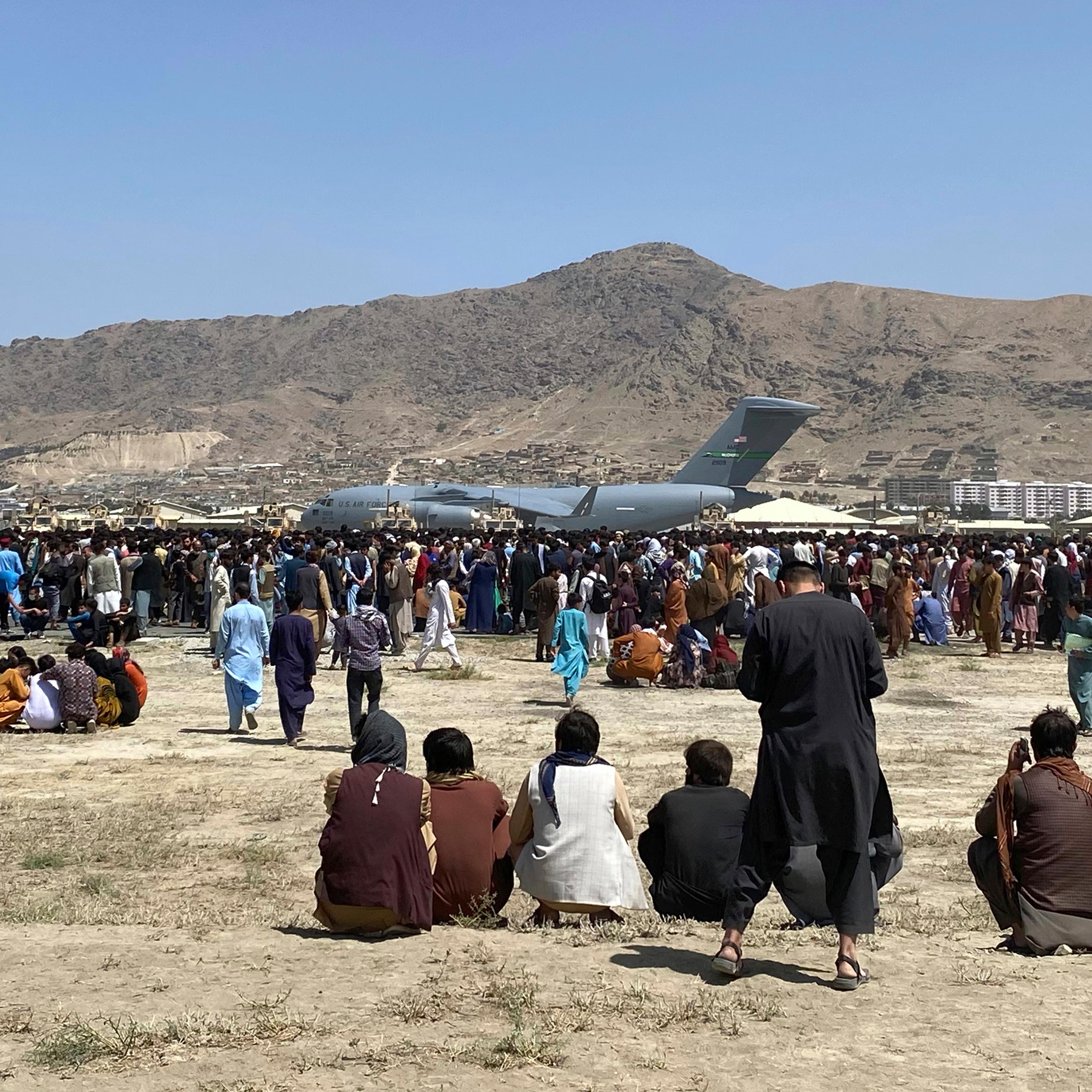 Hundreds of people gather near a U.S. Air Force C-17 transport plane at a perimeter at the international airport in Kabul on Monday, Aug. 16.
