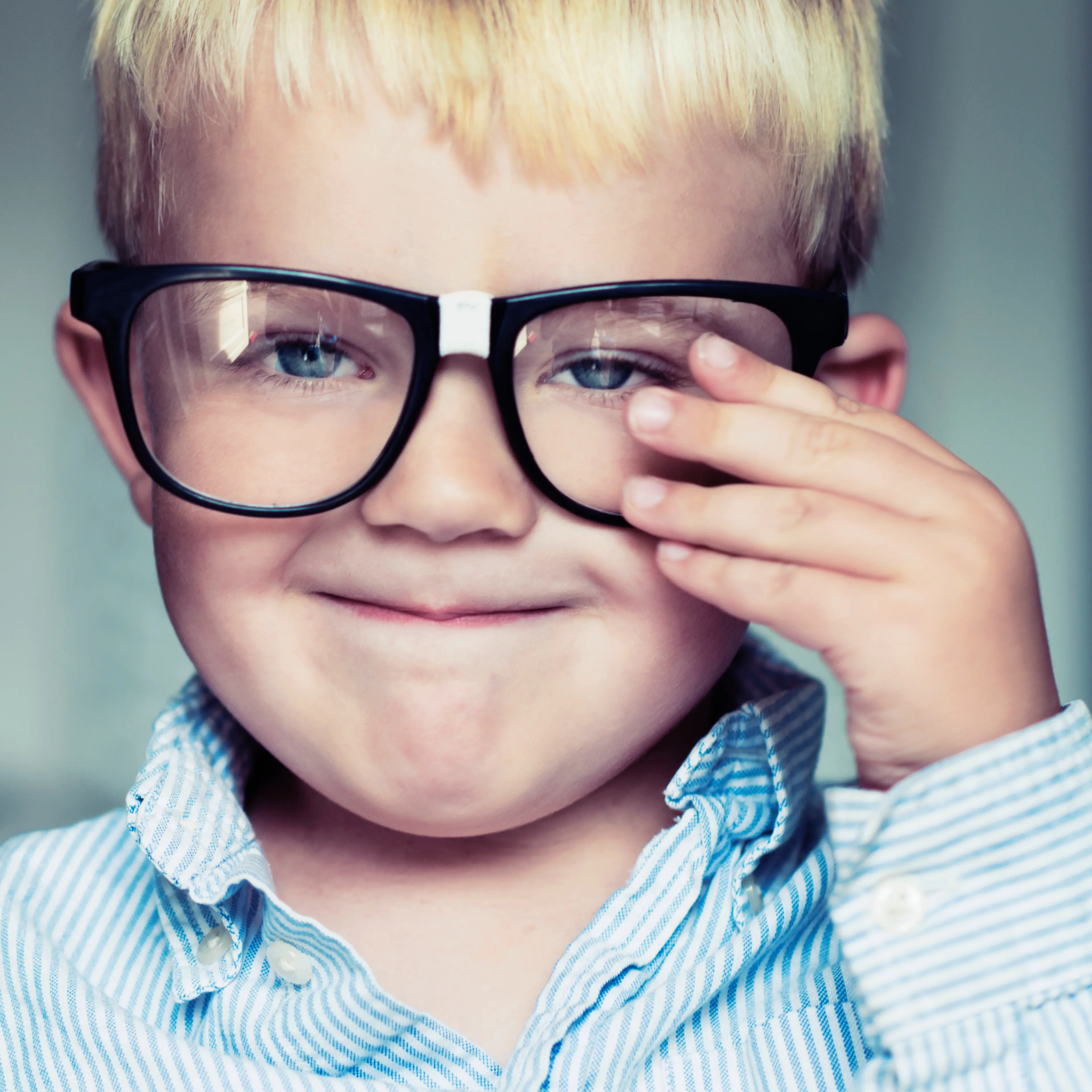 Little boy makes a face while adjusting glasses