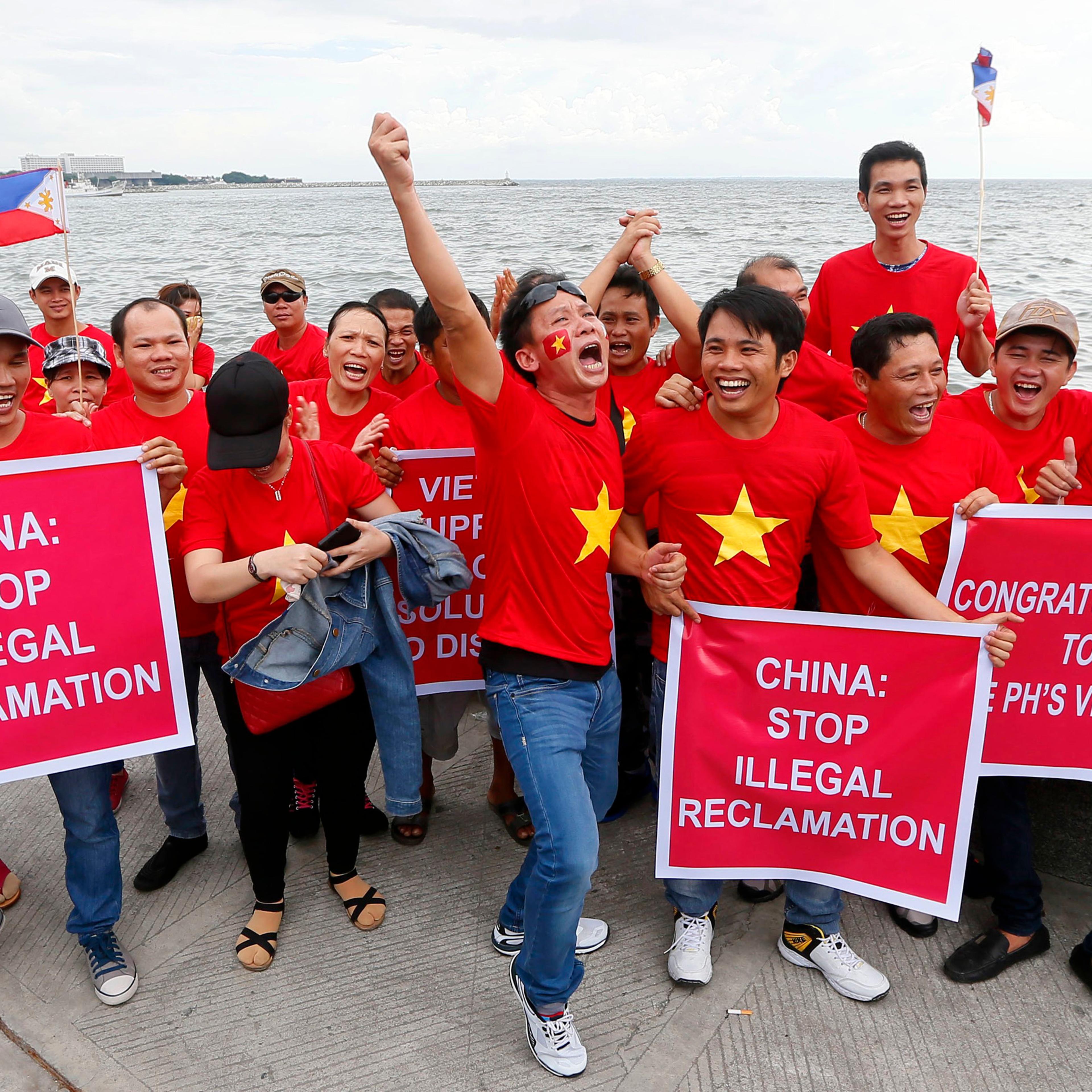 Vietnamese expatriates cheer while displaying placards during a rally by the Manila's baywalk before the Hague-based U.N. international arbitration tribunal is to announce its ruling on South China Sea in the Philippines on July 12, 2016.