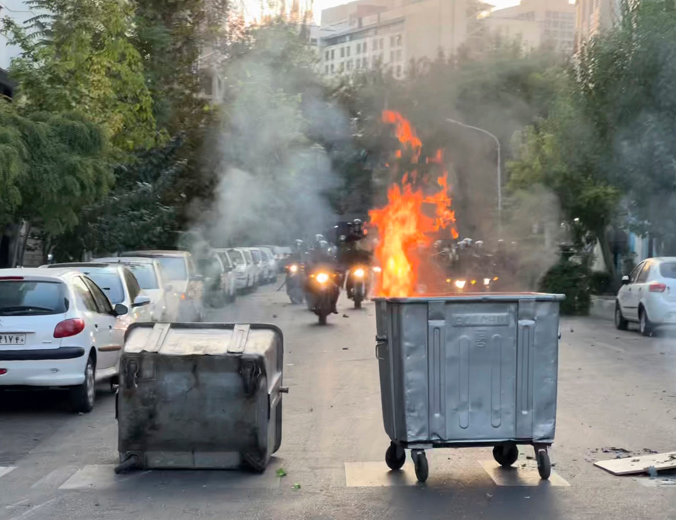 A trash bin is burning as anti-riot police arrive on Sept. 20 during a protest over the death of a young woman, Mahsa Amini, who had been detained for violating the country's conservative dress code, in downtown Tehran, Iran.