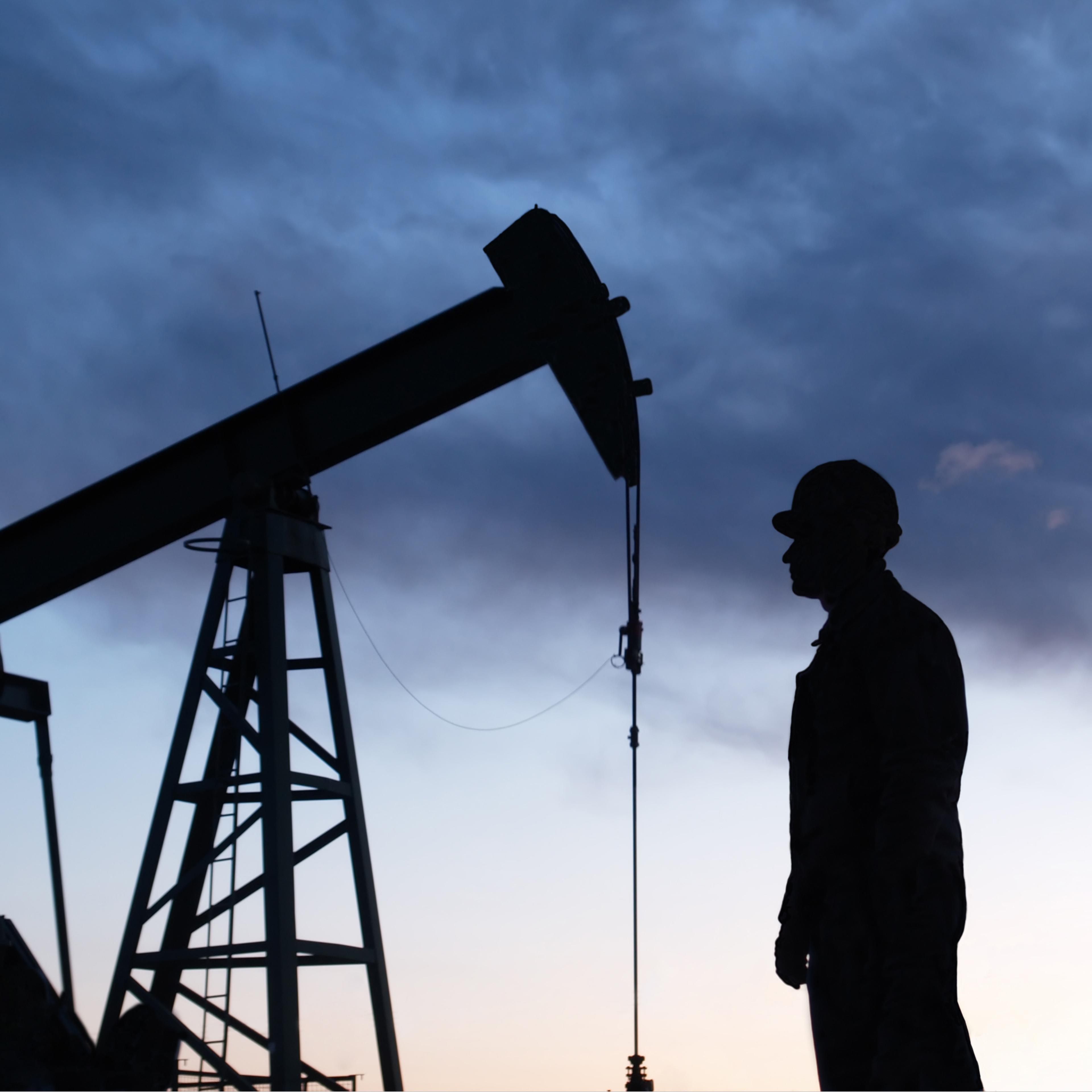 Man looking at oil rig in silhouette