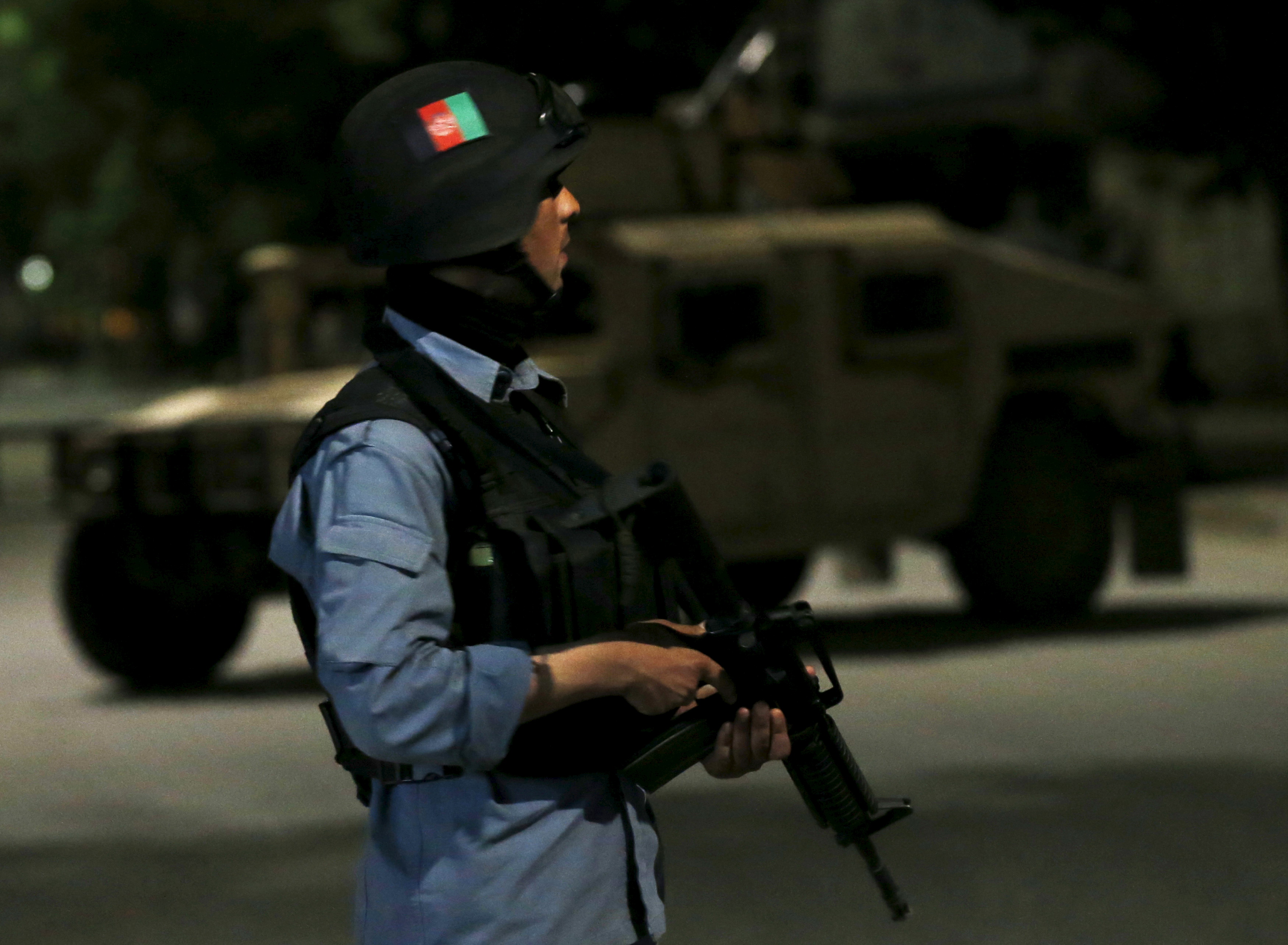 Afghan policeman stands guard at the site of an attack in Kabul, Afghanistan