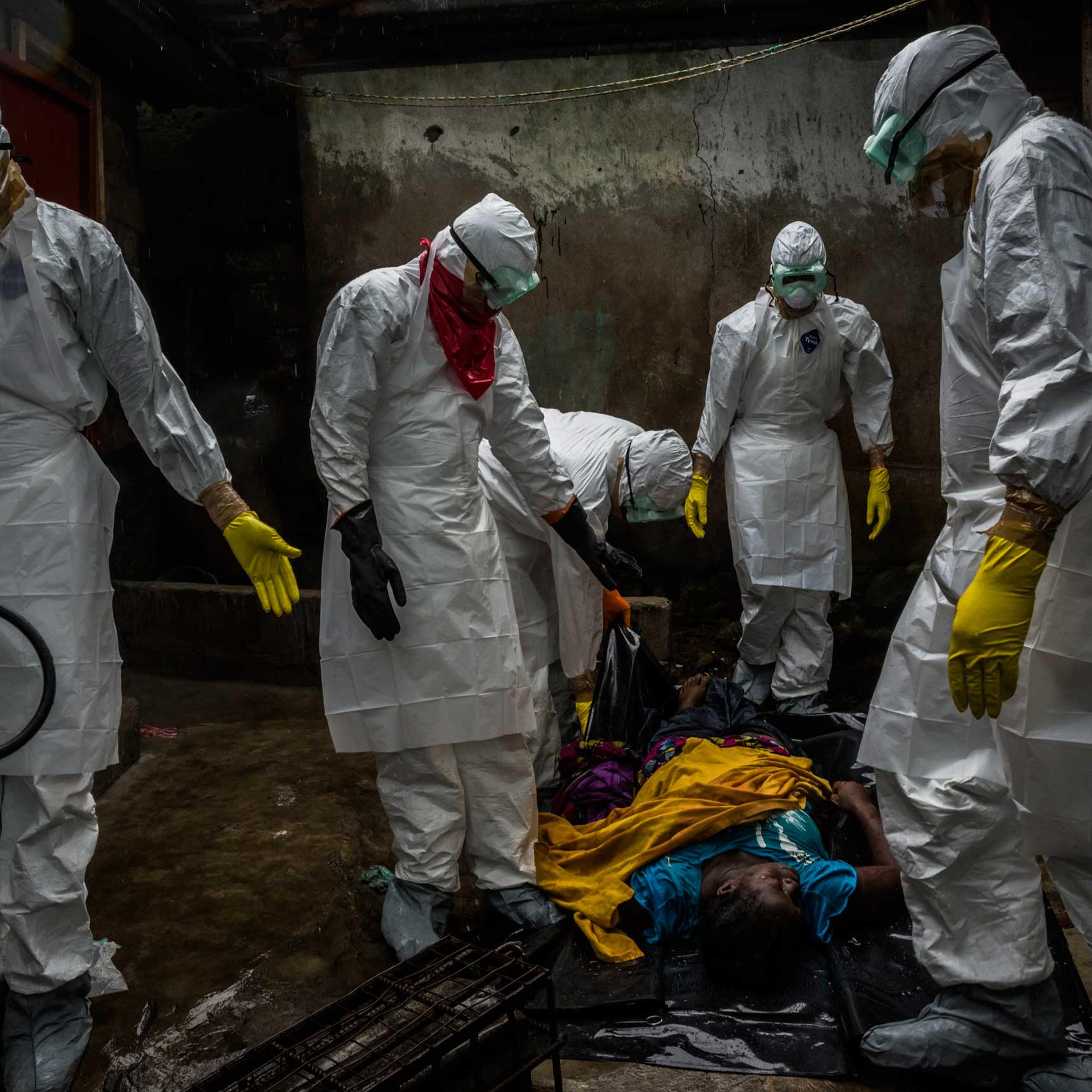 Members of a Liberian Red Cross burial team, under contract from the Liberian Ministry of Health, remove the body of suspected Ebola victim Lorpu David, 30, on Sept. 18, 2014, in the Gurley street community in central Monrovia, Liberia.
