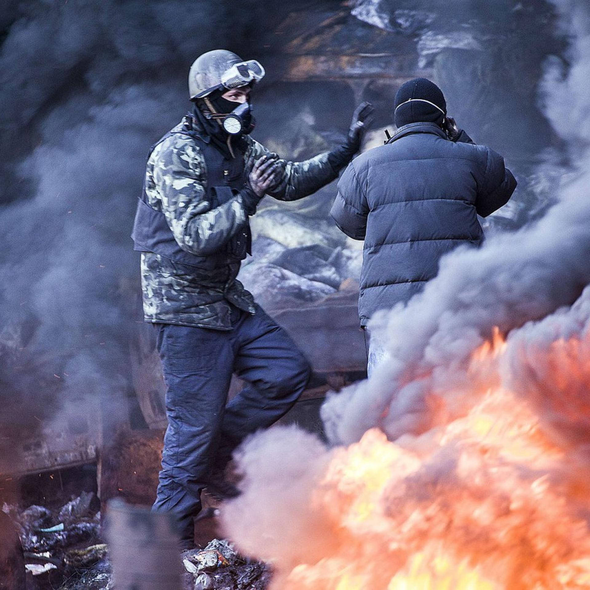 Anti-government demonstrators stand among the smoke of burning barricades during clashes with riot police in Kiev, February 18, 2014.