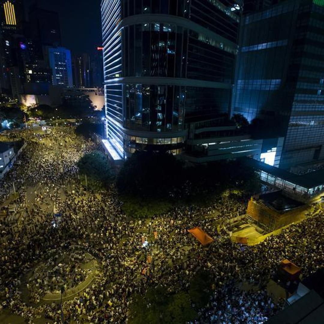 Thousands of protesters attend a rally outside the government headquarters in Hong Kong as riot police stand guard