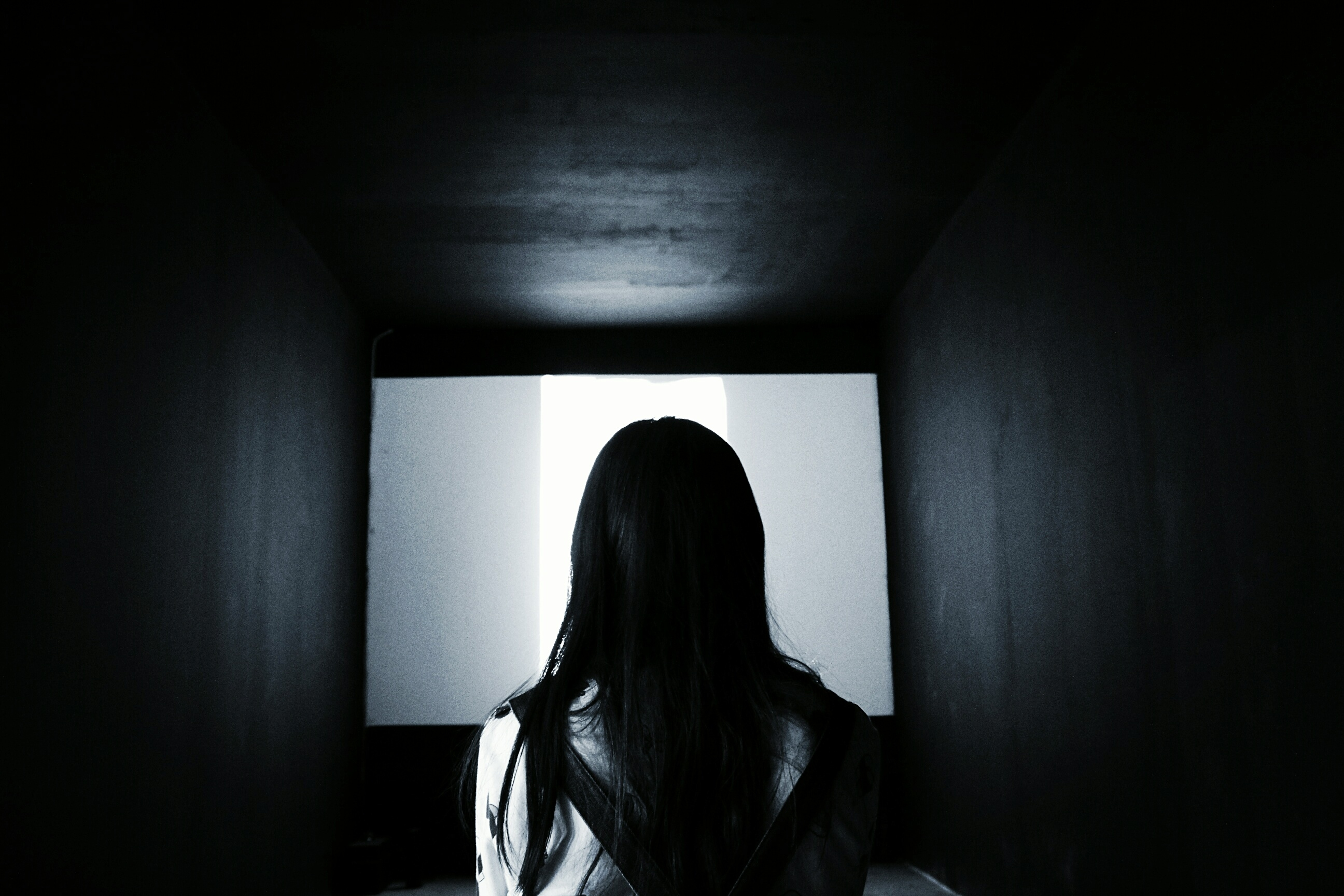 Rear View Of Woman Looking At Projection Screen In Darkroom