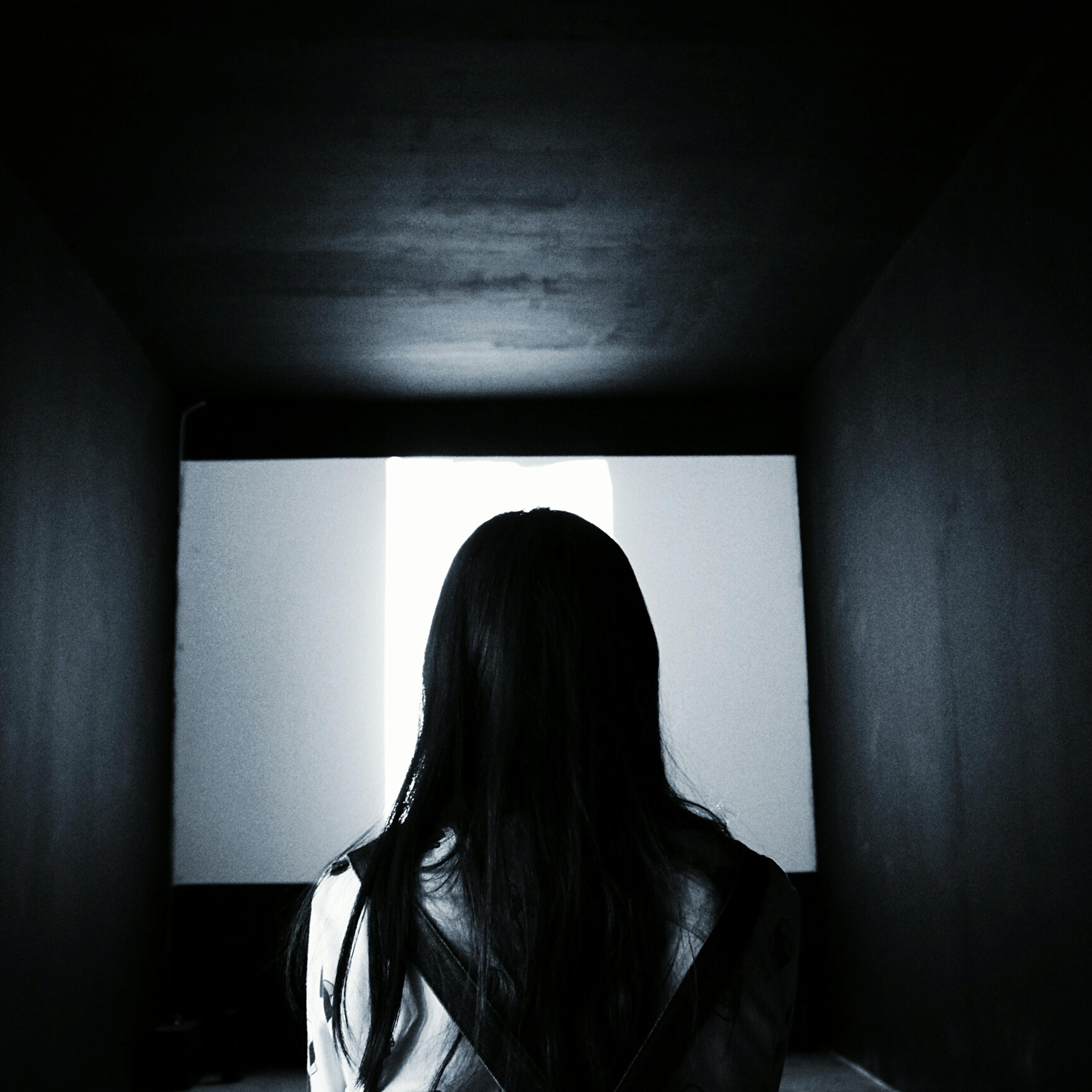 Rear View Of Woman Looking At Projection Screen In Darkroom
