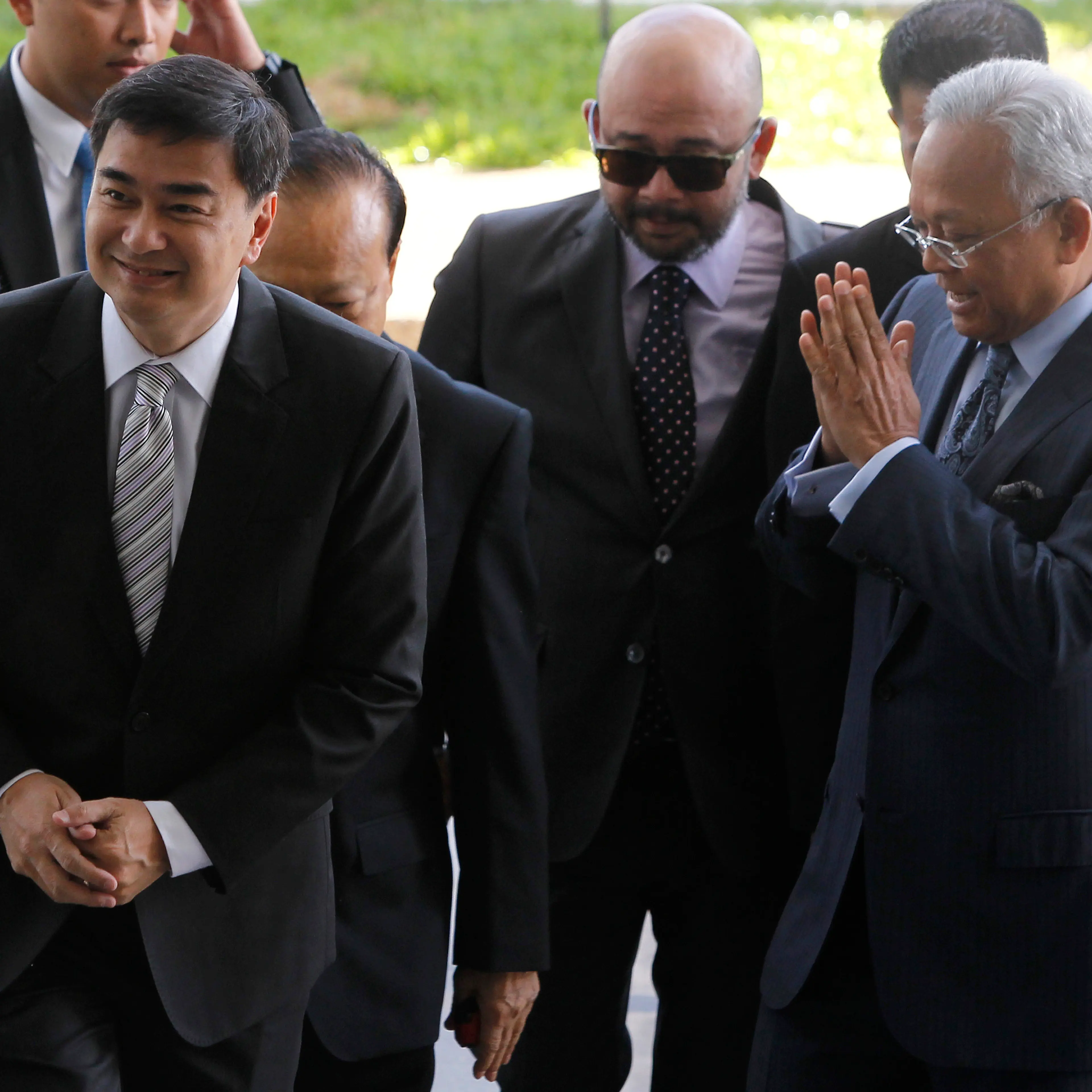 Former Thai Prime Minister Vejjajiva and his then deputy Thaugsuban arrive at the Department of Special Investigation in Bangkok