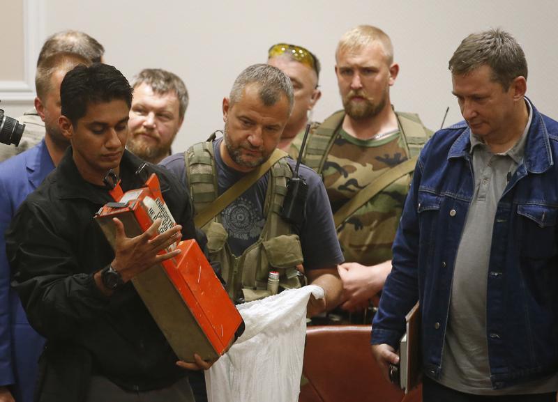 A Malaysian expert examines a black box belonging to Malaysia Airlines MH17 during its handover from pro-Russian separatists, in Donetsk