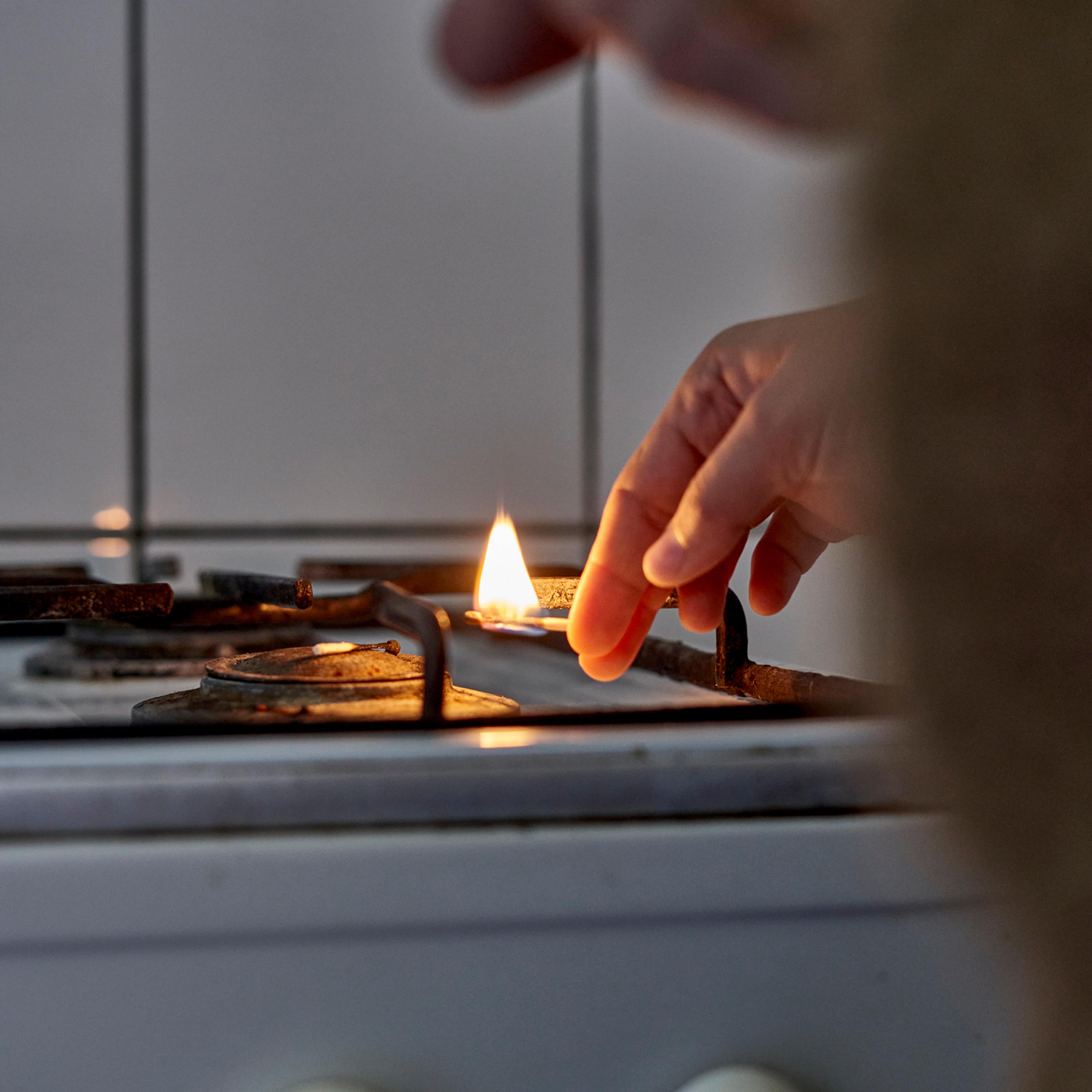 Close-Up Of Hand Lighting Up Gas Stove Burner