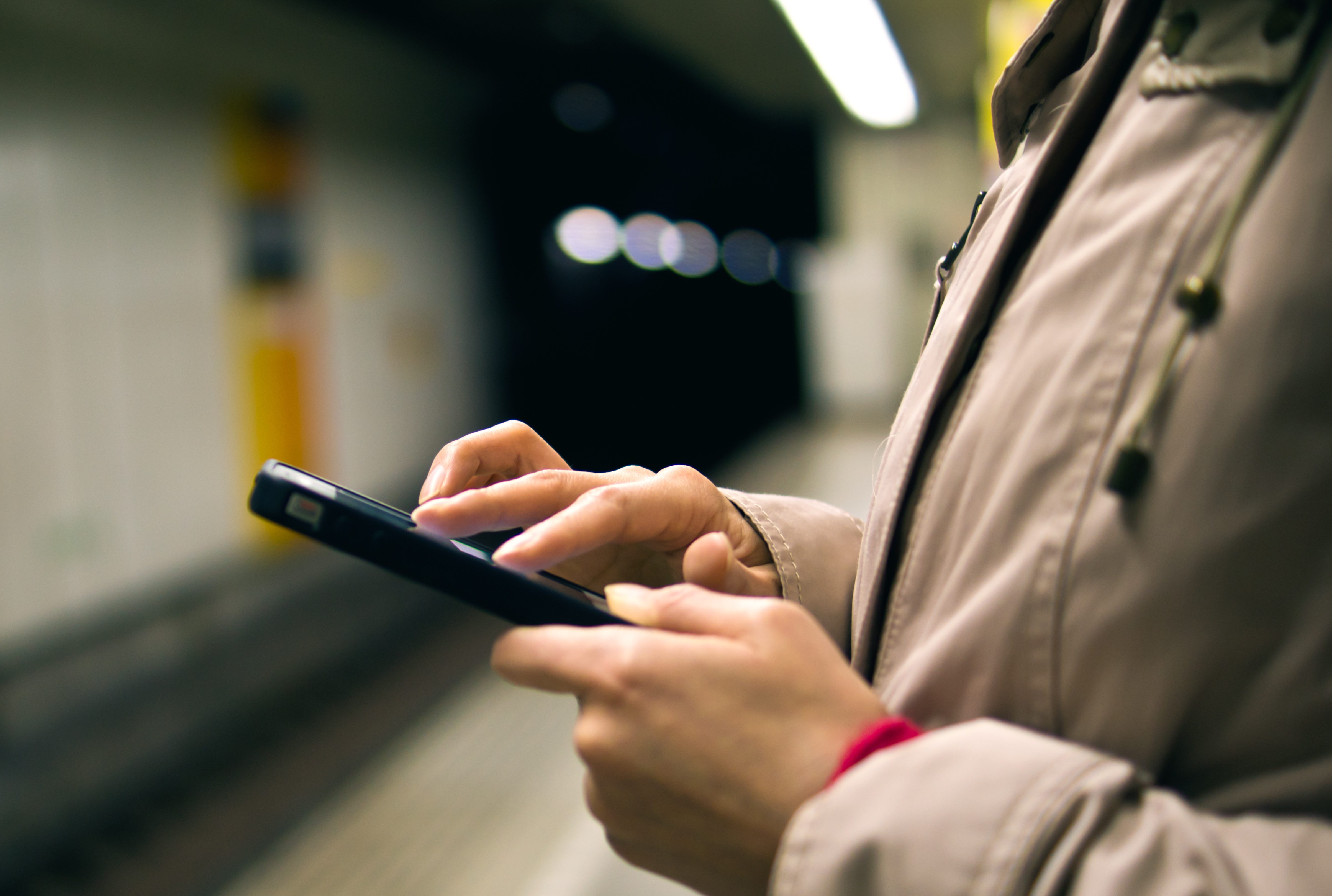 man-holding-smartphone-underground-station