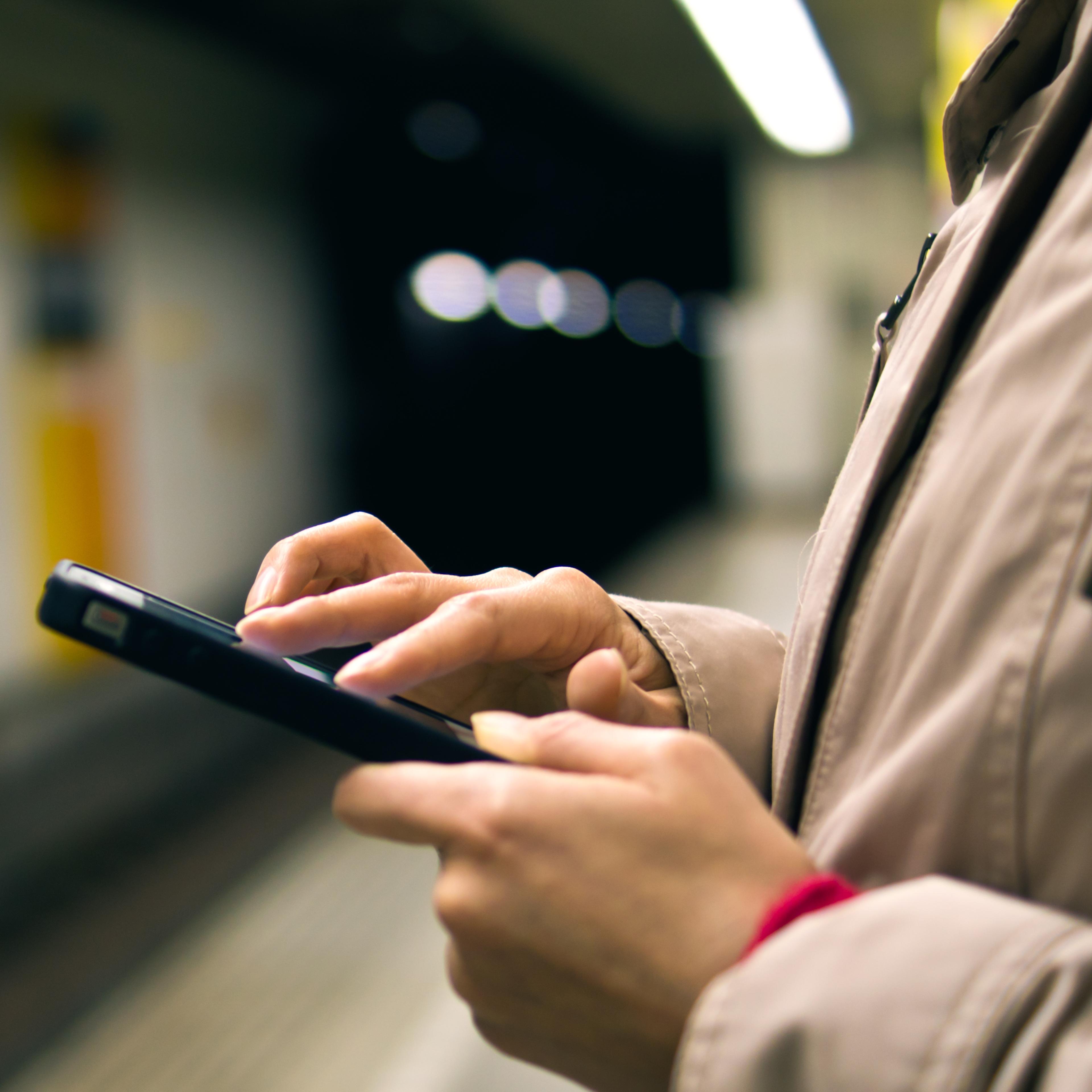 man-holding-smartphone-underground-station