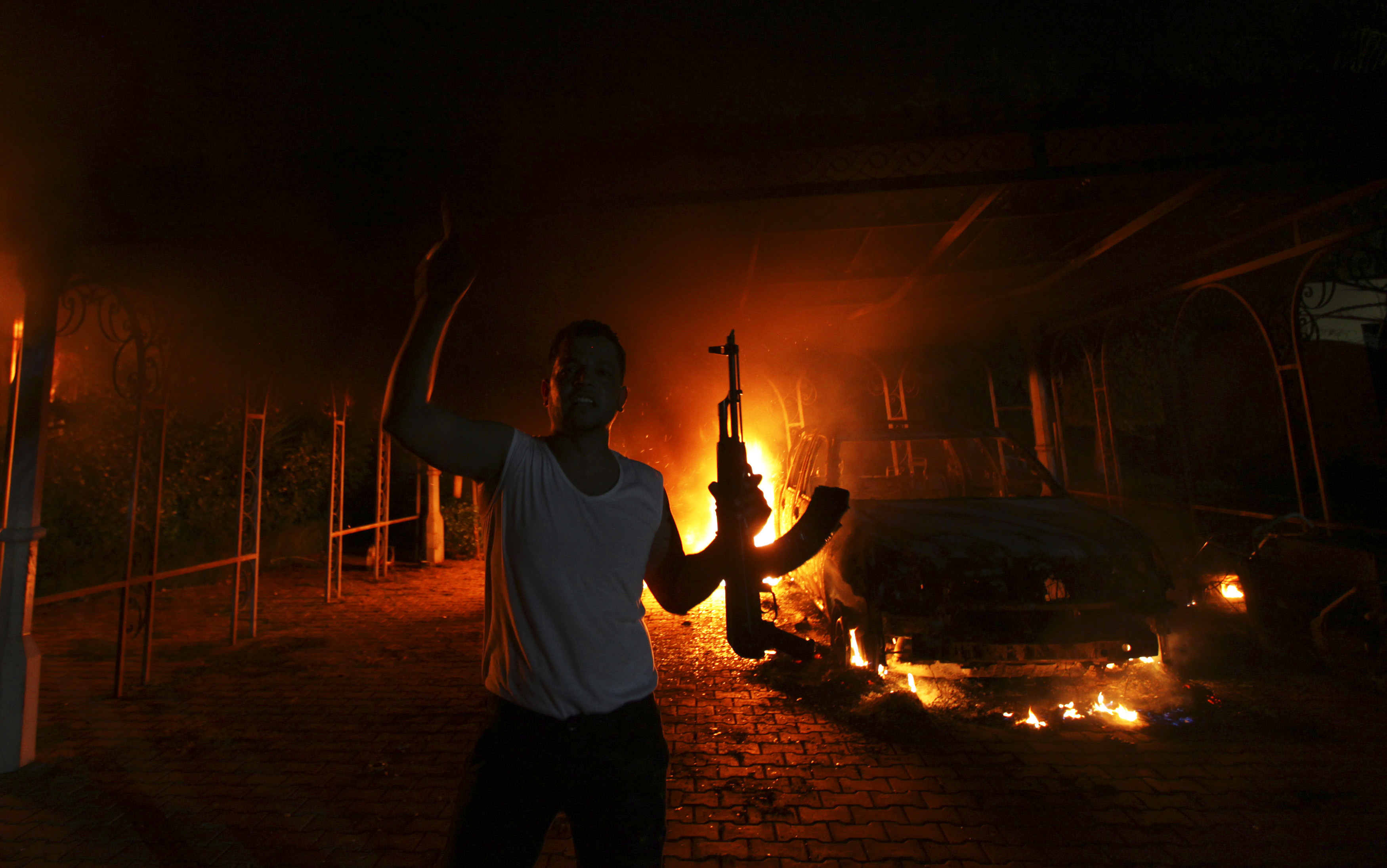 A protester reacts as the U.S. Consulate in Benghazi is seen in flames during a protest by an armed group said to have been protesting a film being produced in the United States on September 11, 2012.