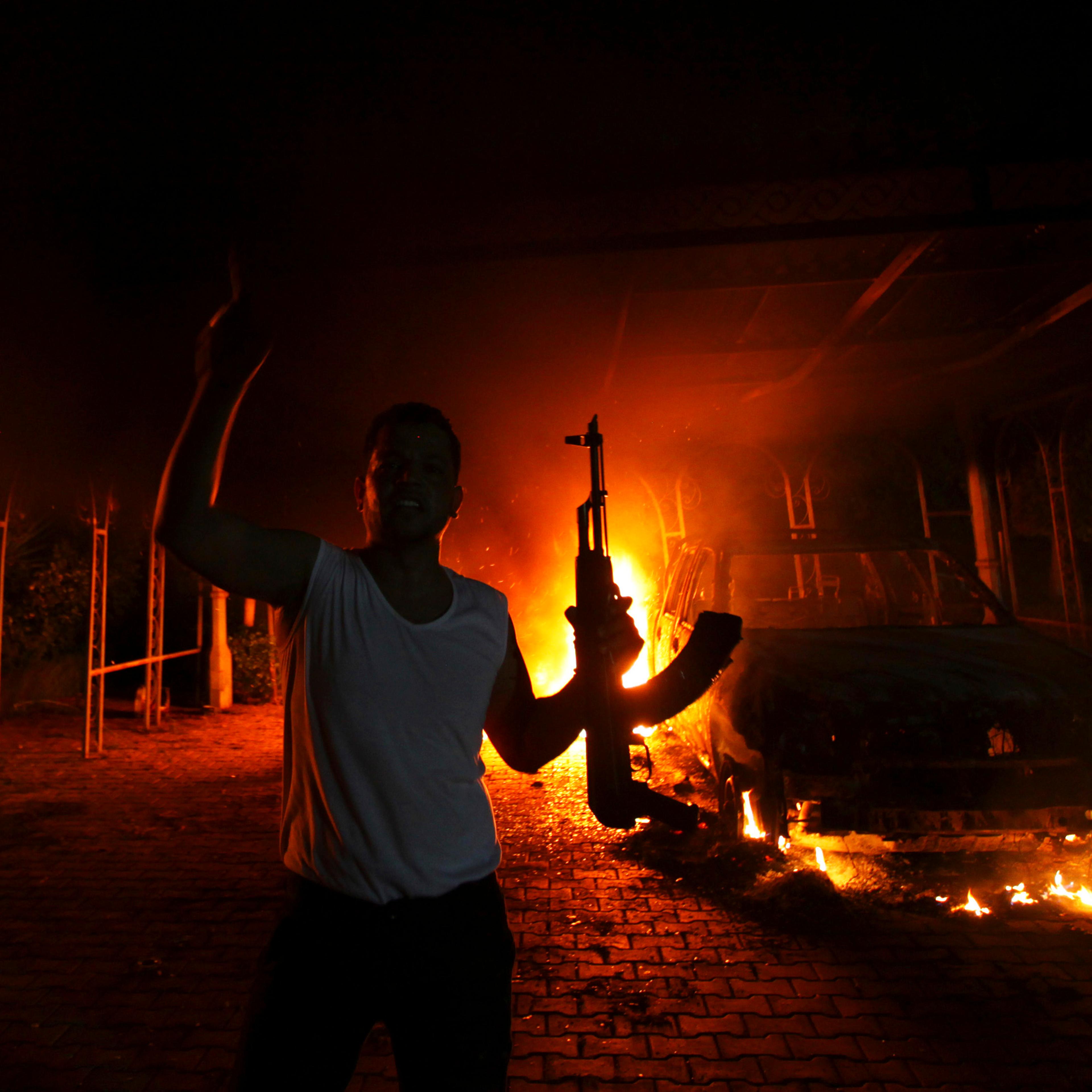 A protester reacts as the U.S. Consulate in Benghazi is seen in flames during a protest by an armed group said to have been protesting a film being produced in the United States on September 11, 2012.