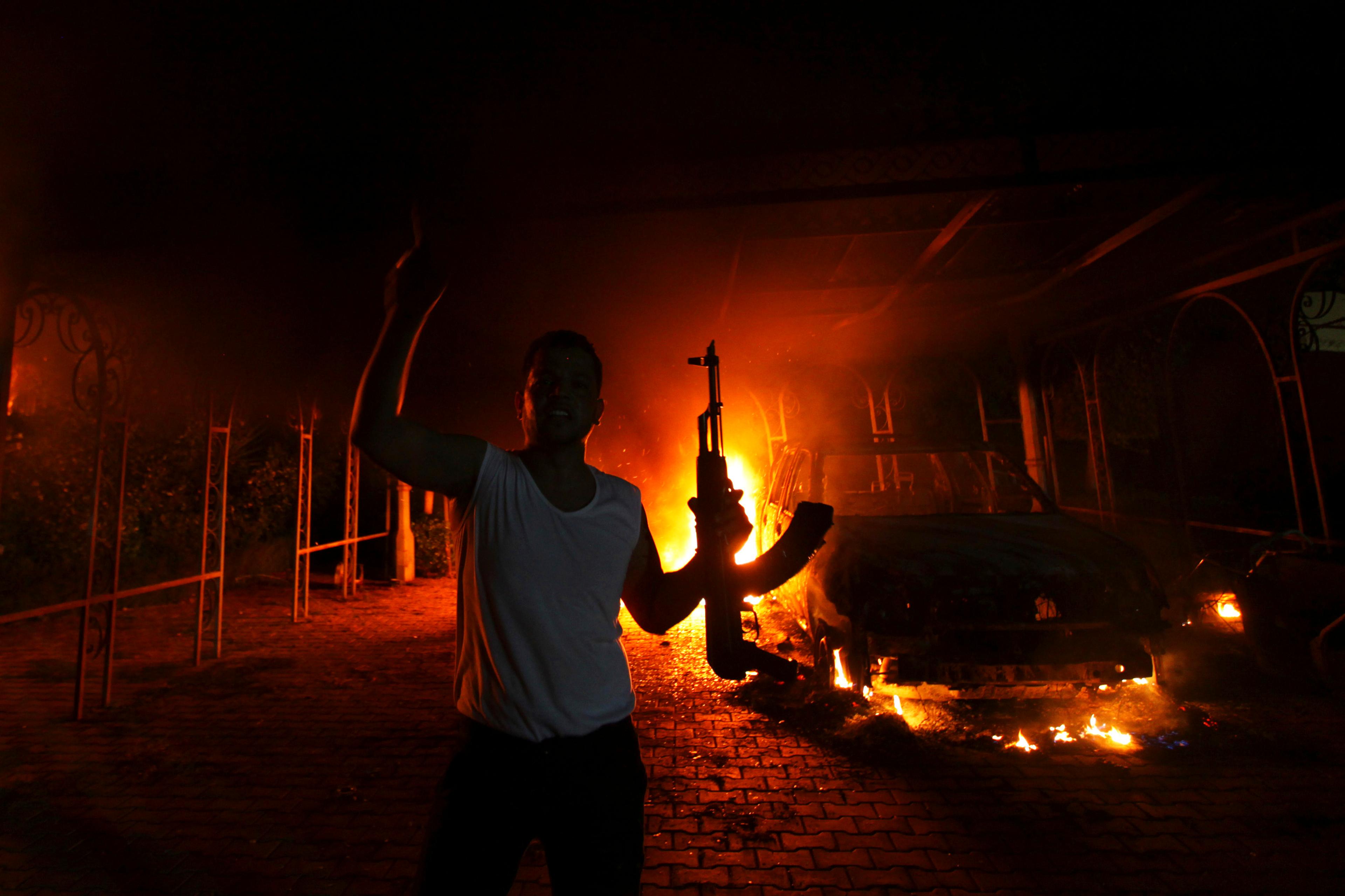 A protester reacts as the U.S. Consulate in Benghazi is seen in flames during a protest by an armed group said to have been protesting a film being produced in the United States on September 11, 2012.