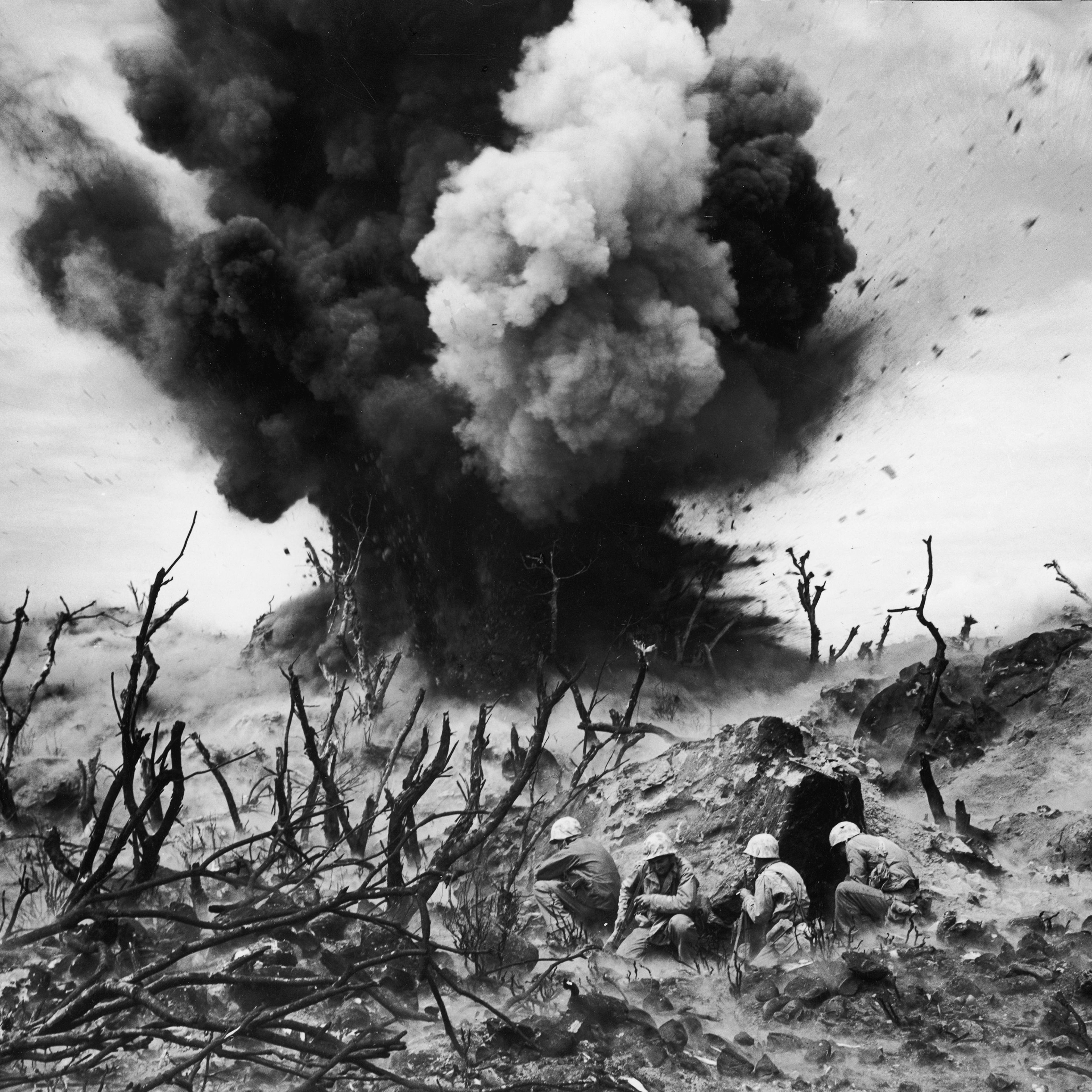 United States Marines (foreground) blow up a cave connected to a Japanese blockhouse on Iwo Jima, March 1945.