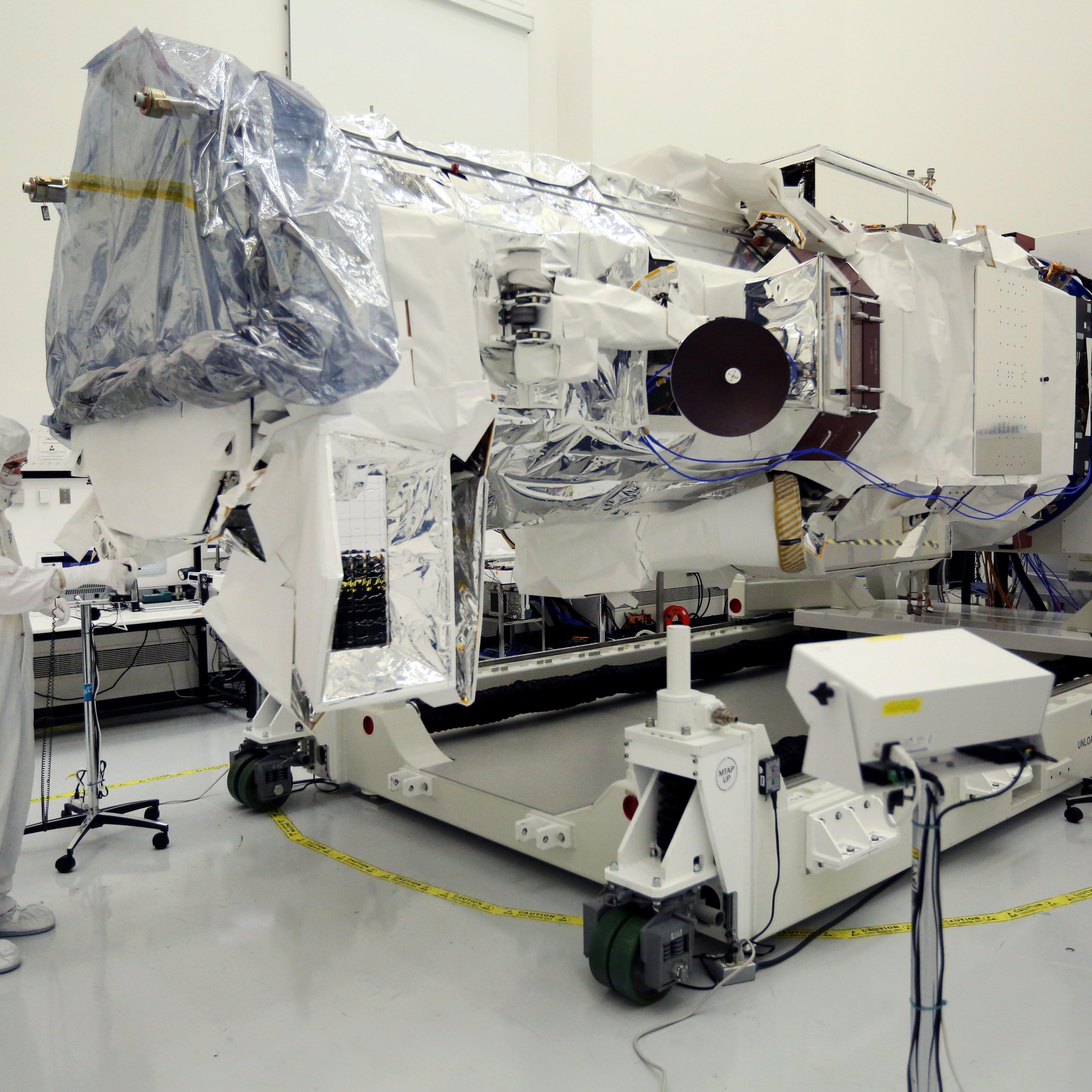 A technician wearing a clean suit runs tests on WorldView-3, a new high-resolution imaging satellite owned by commercial satellite company DigitalGlobe, at Ball Aerospace in Boulder, Colo., on Tuesday, May 13, 2014.