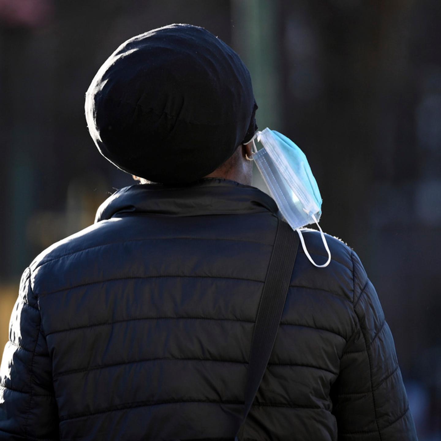 A person wears their mask dangling off an ear during the 2024 COVID-19 surge.