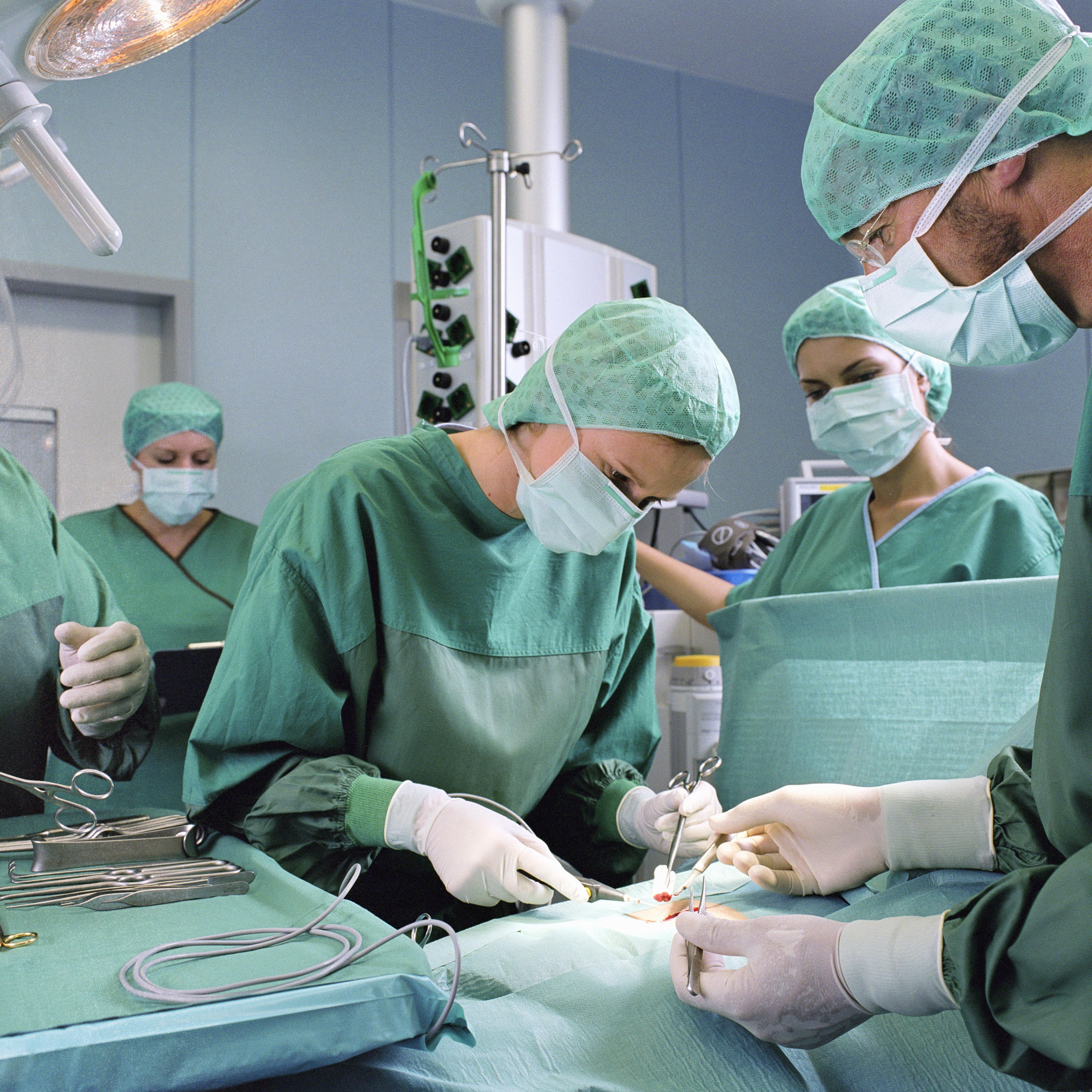 A group of surgeons work in an operating theatre.