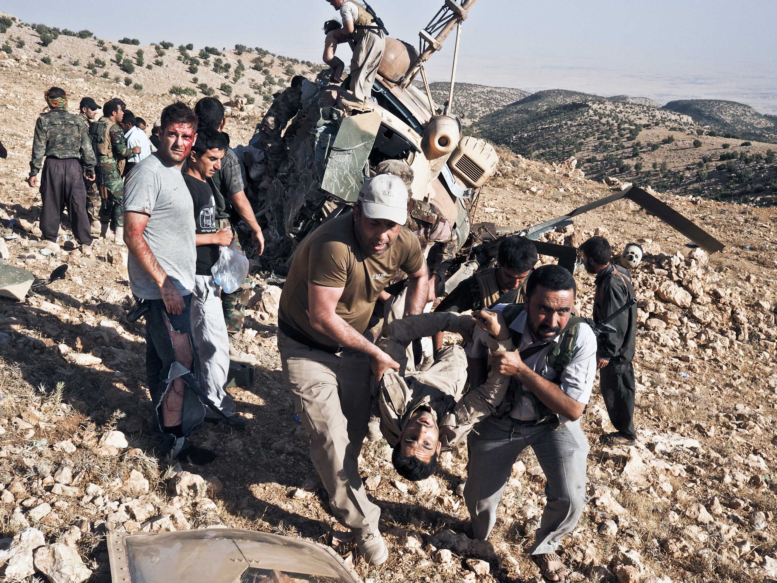 A wounded man is carried away from an Iraqi Air Force helicopter that crashed shortly after takeoff during a rescue mission. Sinjar Mountains, Iraq, Aug. 12, 2014.