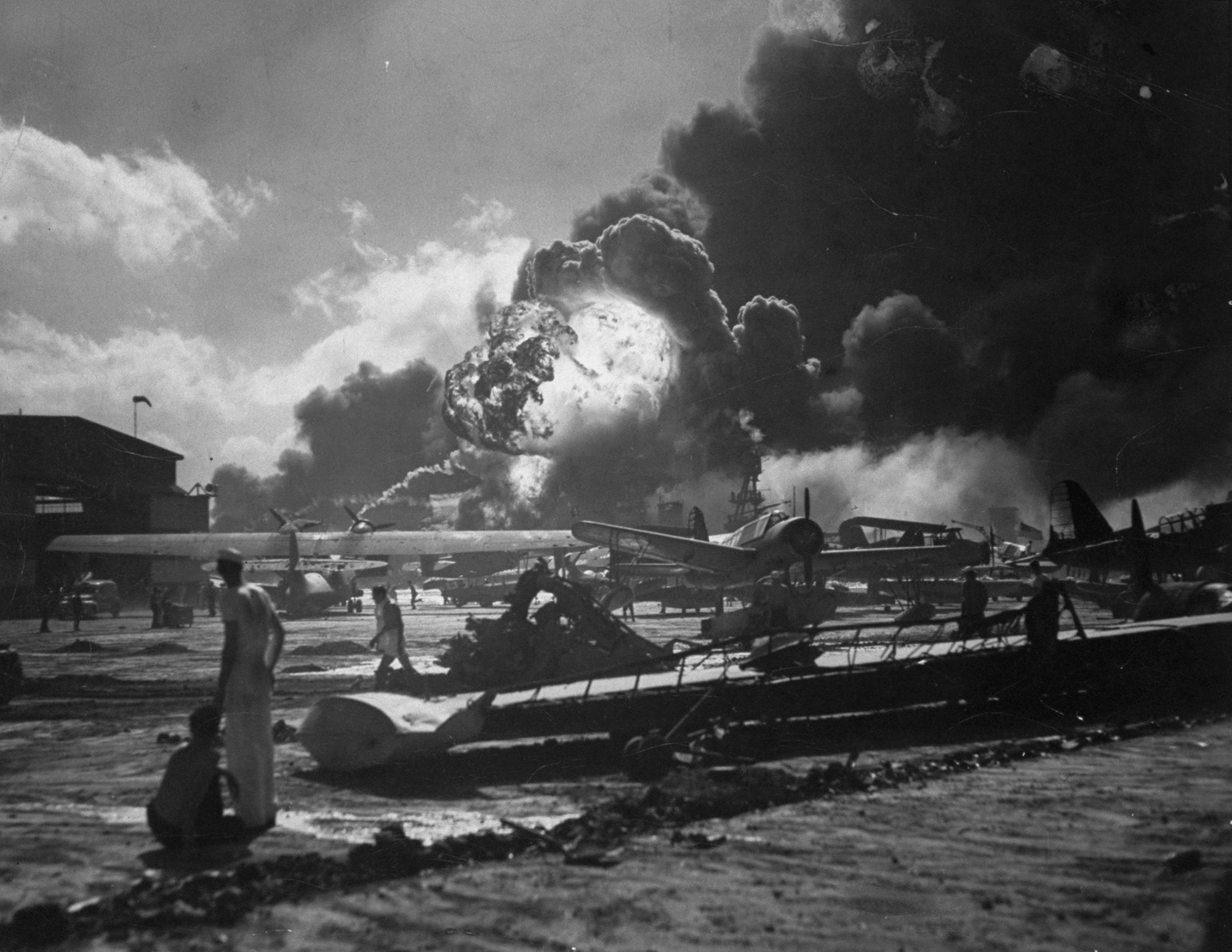 Sailors, planes and a huge ball of fire and smoke at wreckage-strewn Naval Air Station, Hawaii, following one of the Japanese attacks on Pearl Harbor on Dec. 7, 1941.
