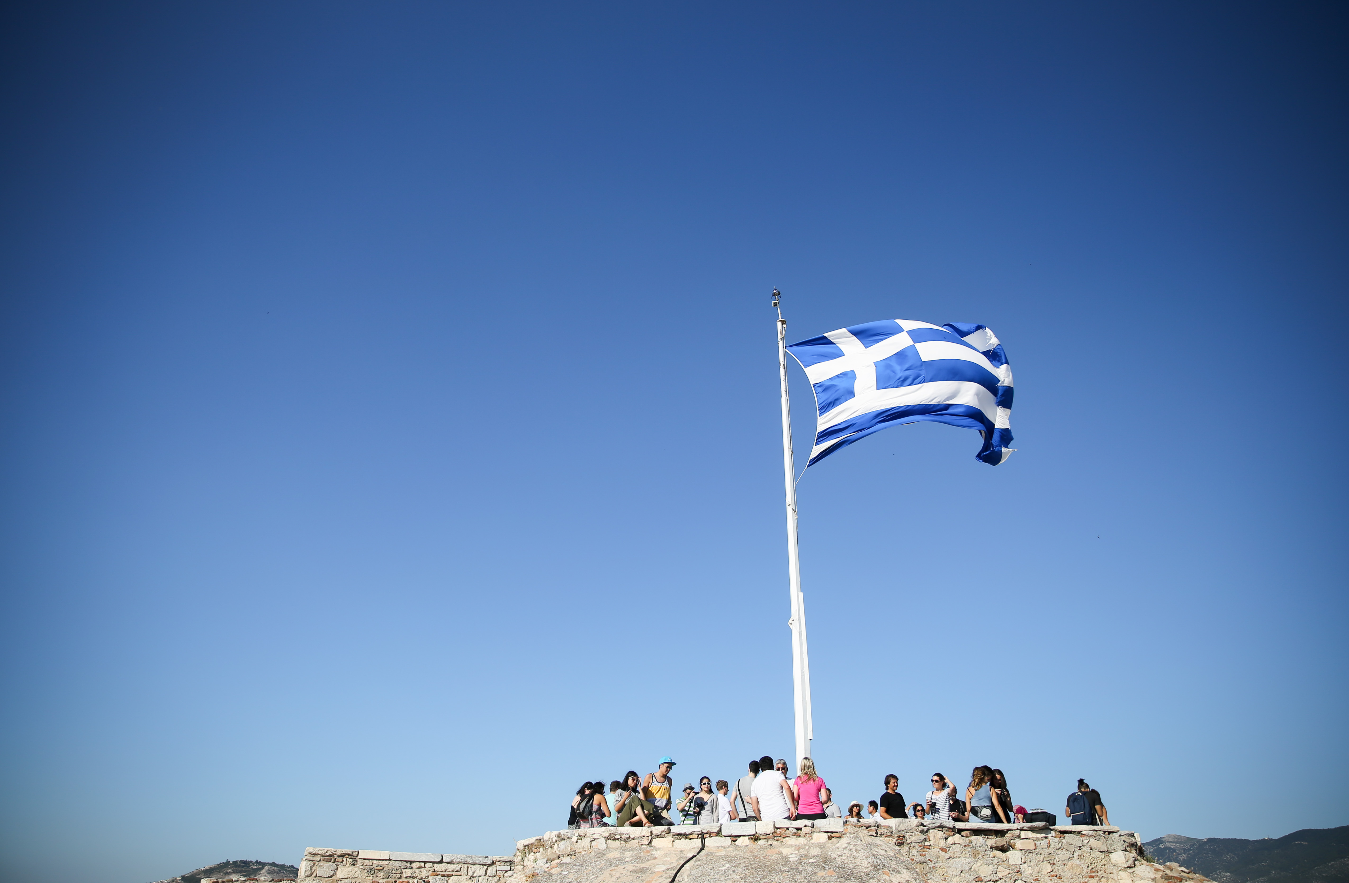 The Greek flag flies in the wind at the Acropolois in Athens on July 4, 2015.