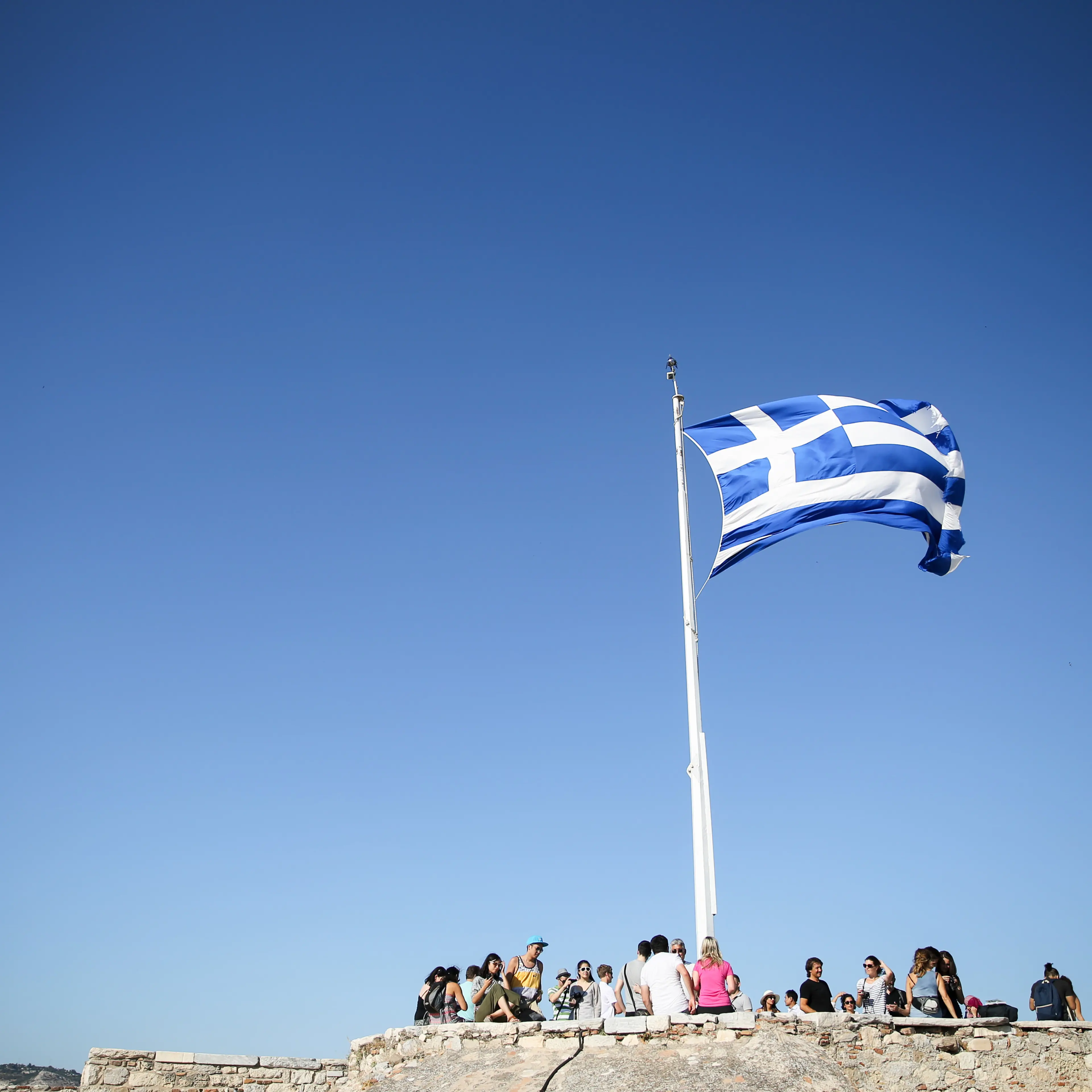 The Greek flag flies in the wind at the Acropolois in Athens on July 4, 2015.