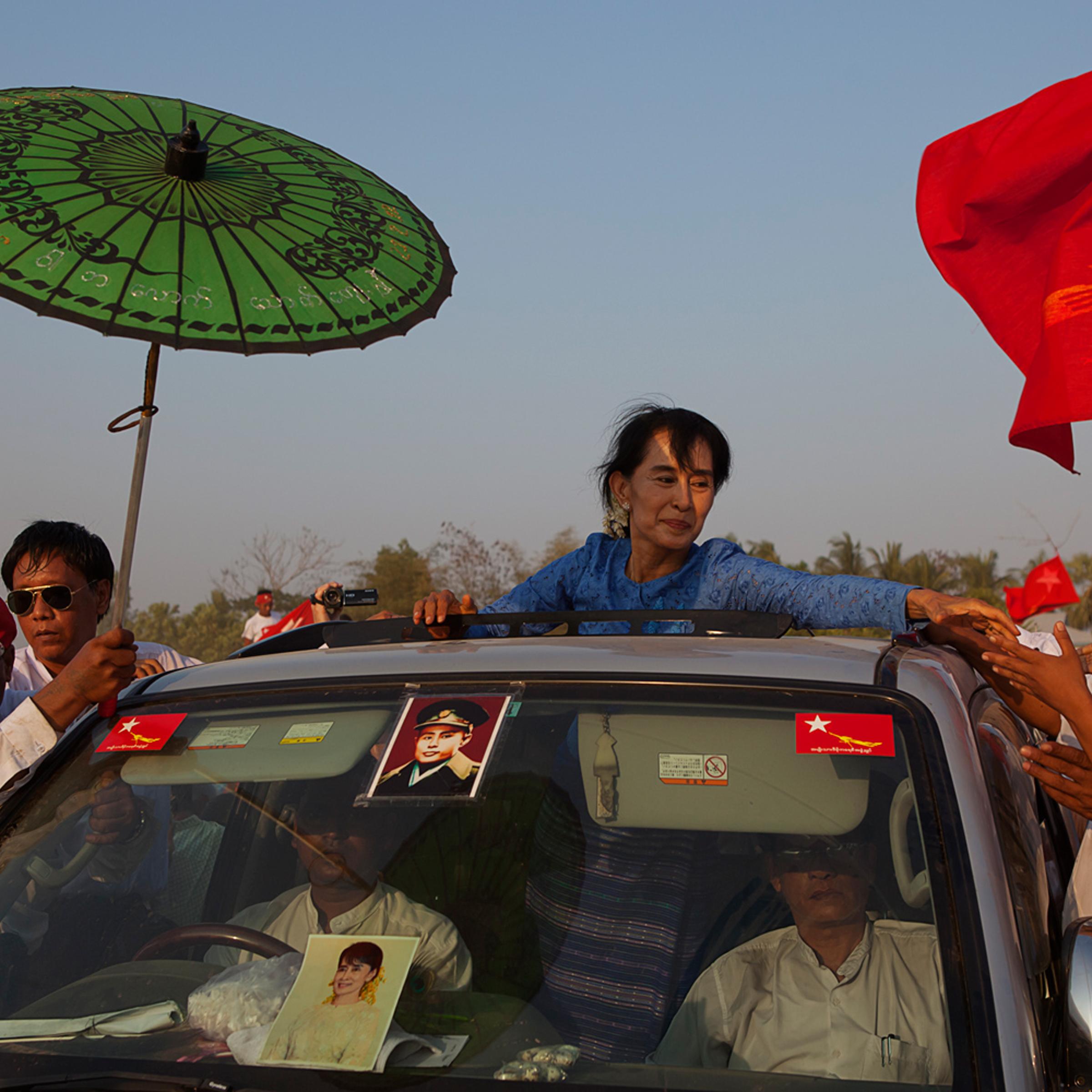 March 22, 2012. Aung San Suu Kyi departs from a campaign rally in Kawhmu, the district from which she ran for a seat in Parliament. She emerges from the sun roof to shake hands with thousands of well-wishers who lined the road. A staff member holds a parasol to protect her from the sun.