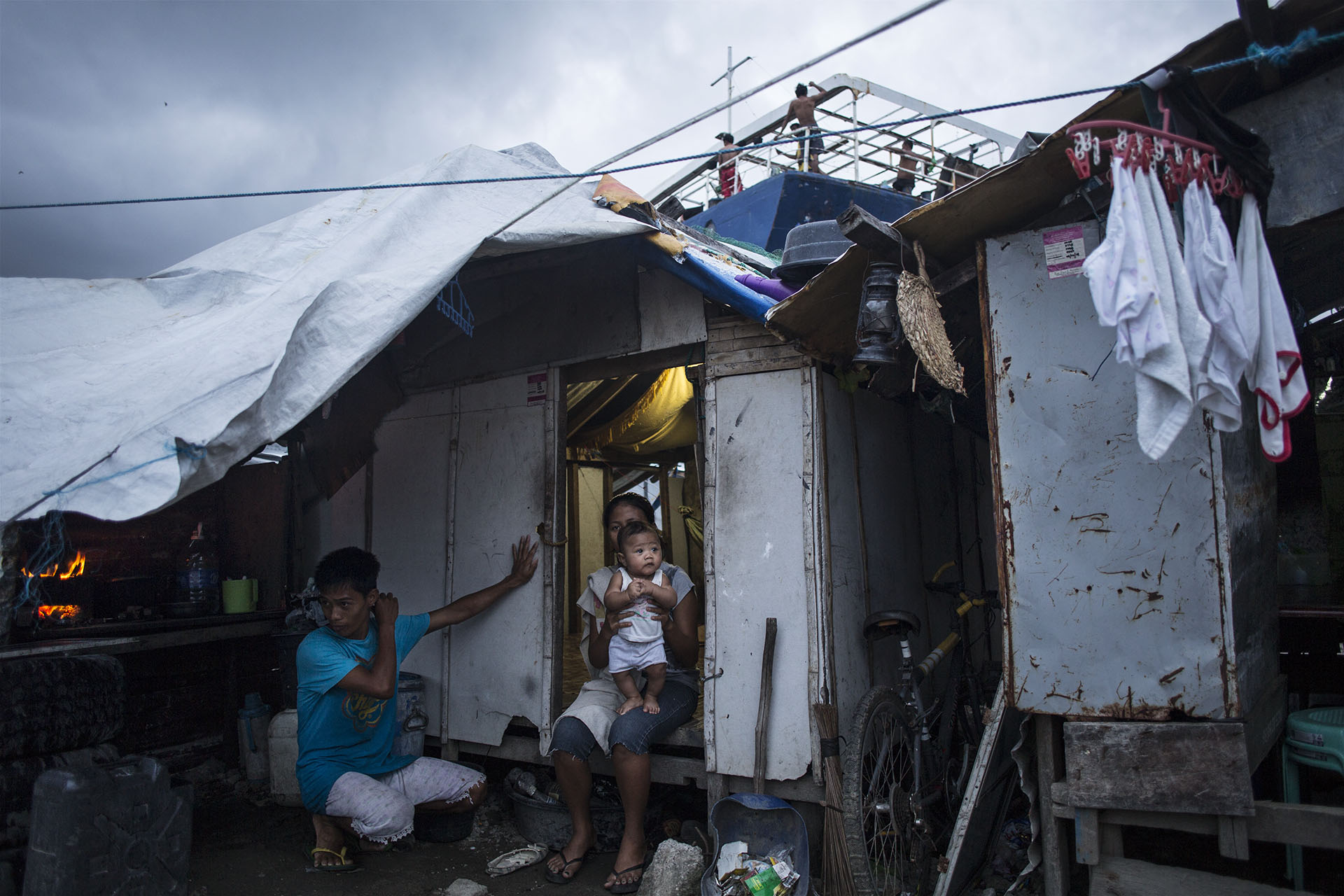 Eric and Roby Mameta by their house in Tacloban, in the Philippines, on Oct. 8, 2014, next to one of the ships that were washed ashore by supertyphoon Haiyan 