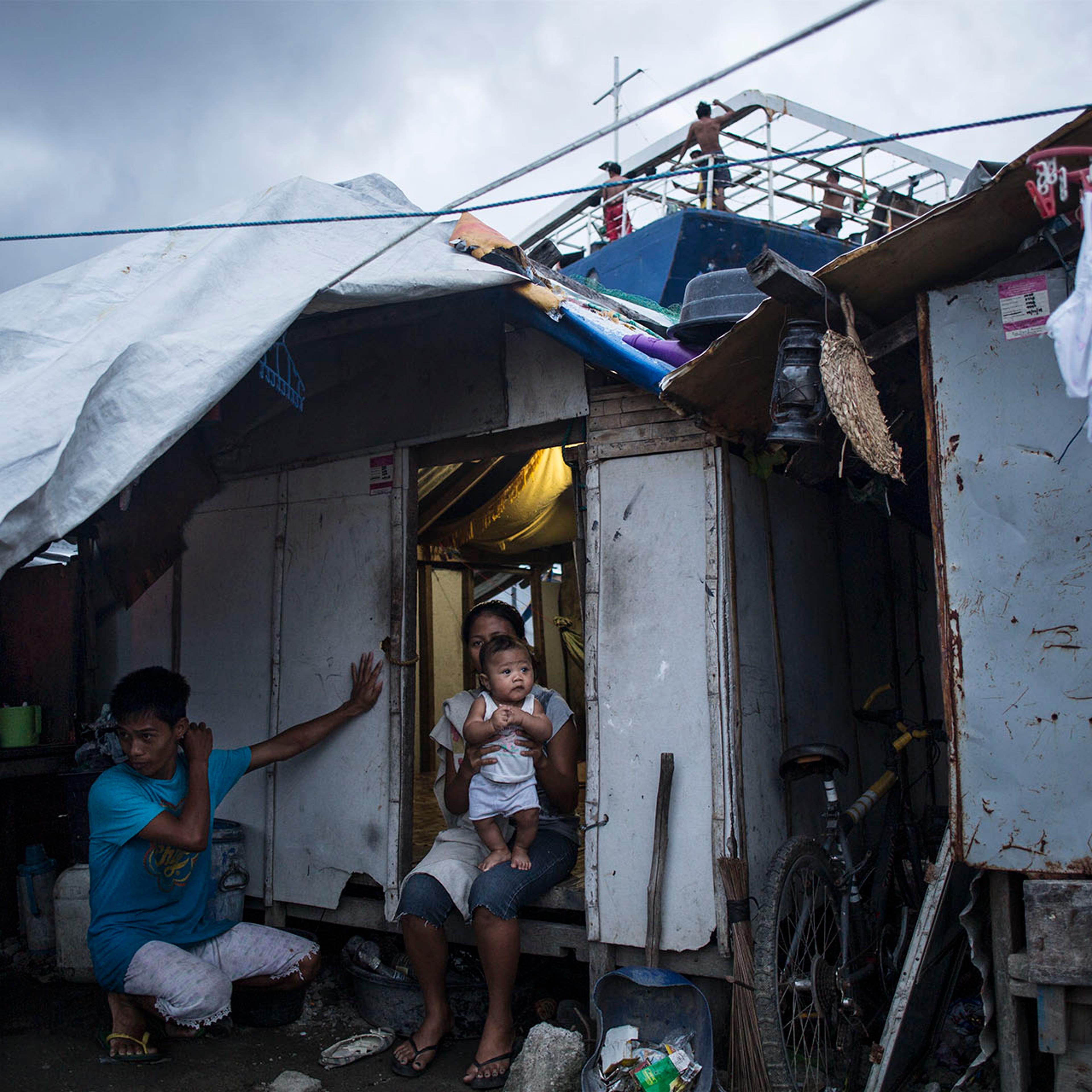 Eric and Roby Mameta by their house in Tacloban, in the Philippines, on Oct. 8, 2014, next to one of the ships that were washed ashore by supertyphoon Haiyan