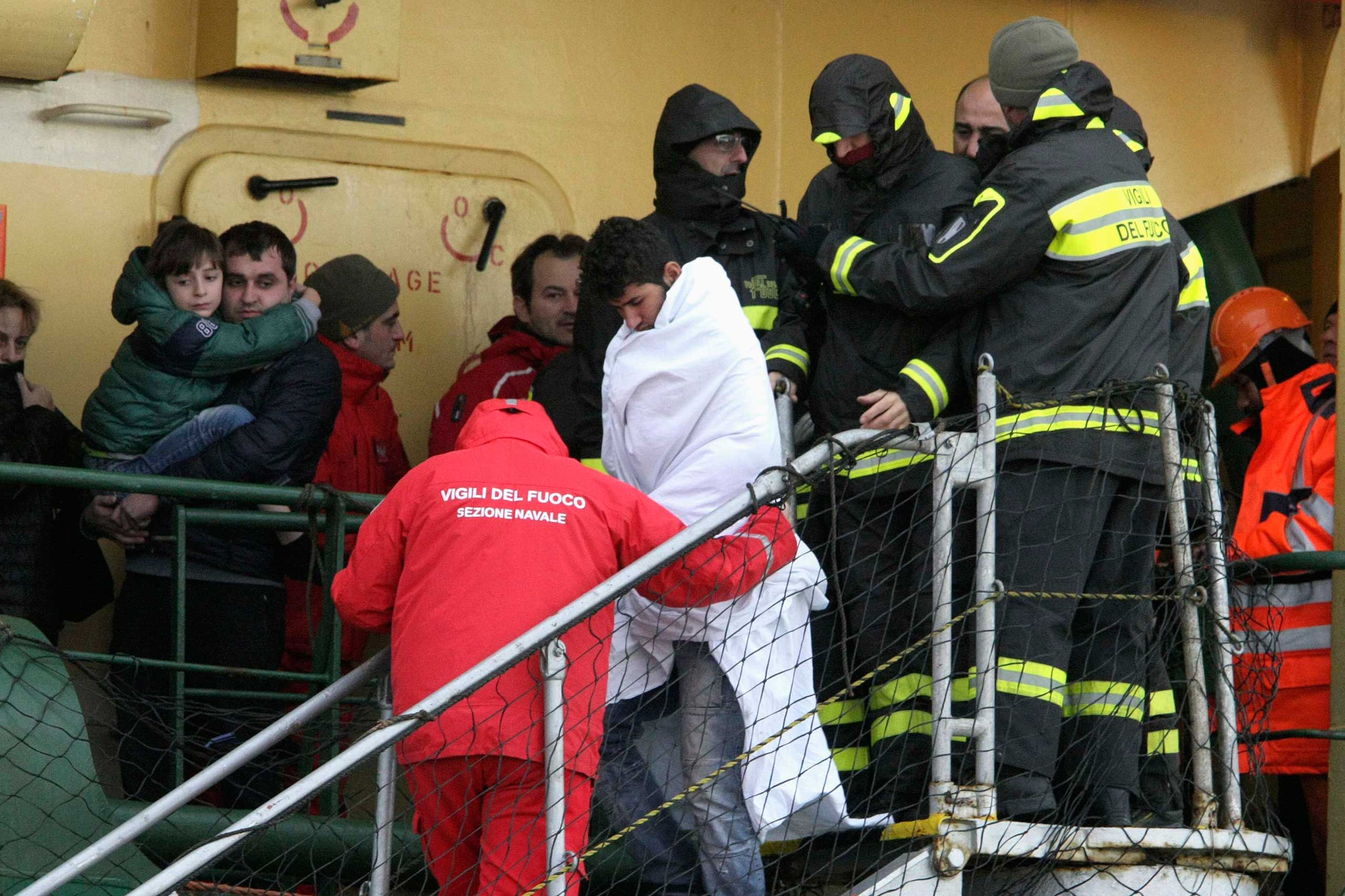 Passenger is helped as he leaves from the " Spirit of Piraeus" cargo container ship as they arrive in Bari harbour, after the car ferry Norman Atlantic caught fire in waters off Greece