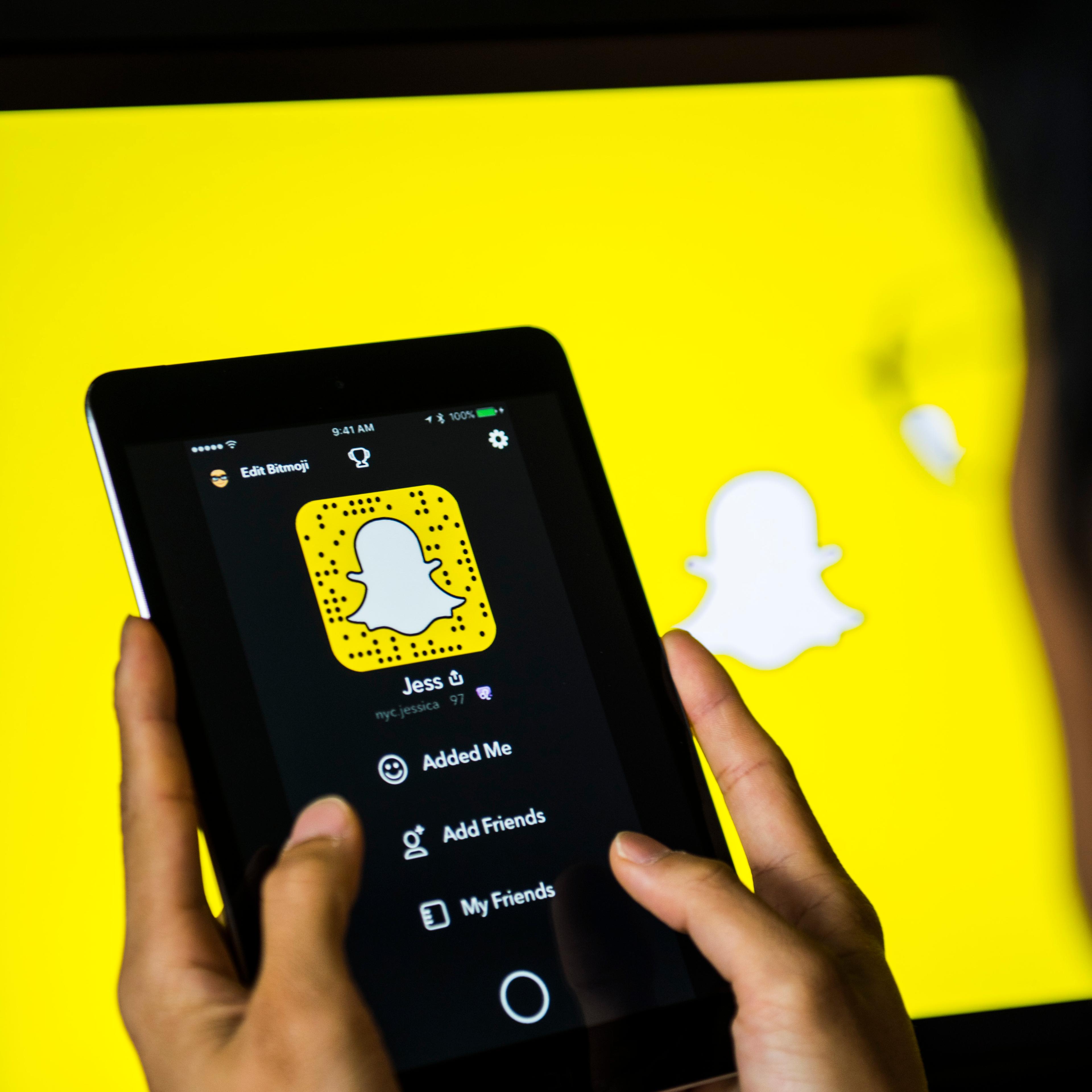 Young man holds a smart device while using SnapChat app